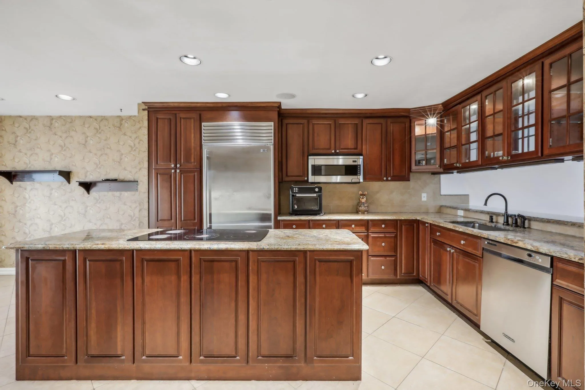 Kitchen featuring light stone countertops, stainless steel appliances, light tile patterned floors, recessed lighting, and glass insert cabinets Kitchen featuring light stone countertops, stainless steel appliances, light tile patterned floors, recessed lighting, and glass insert cabinets