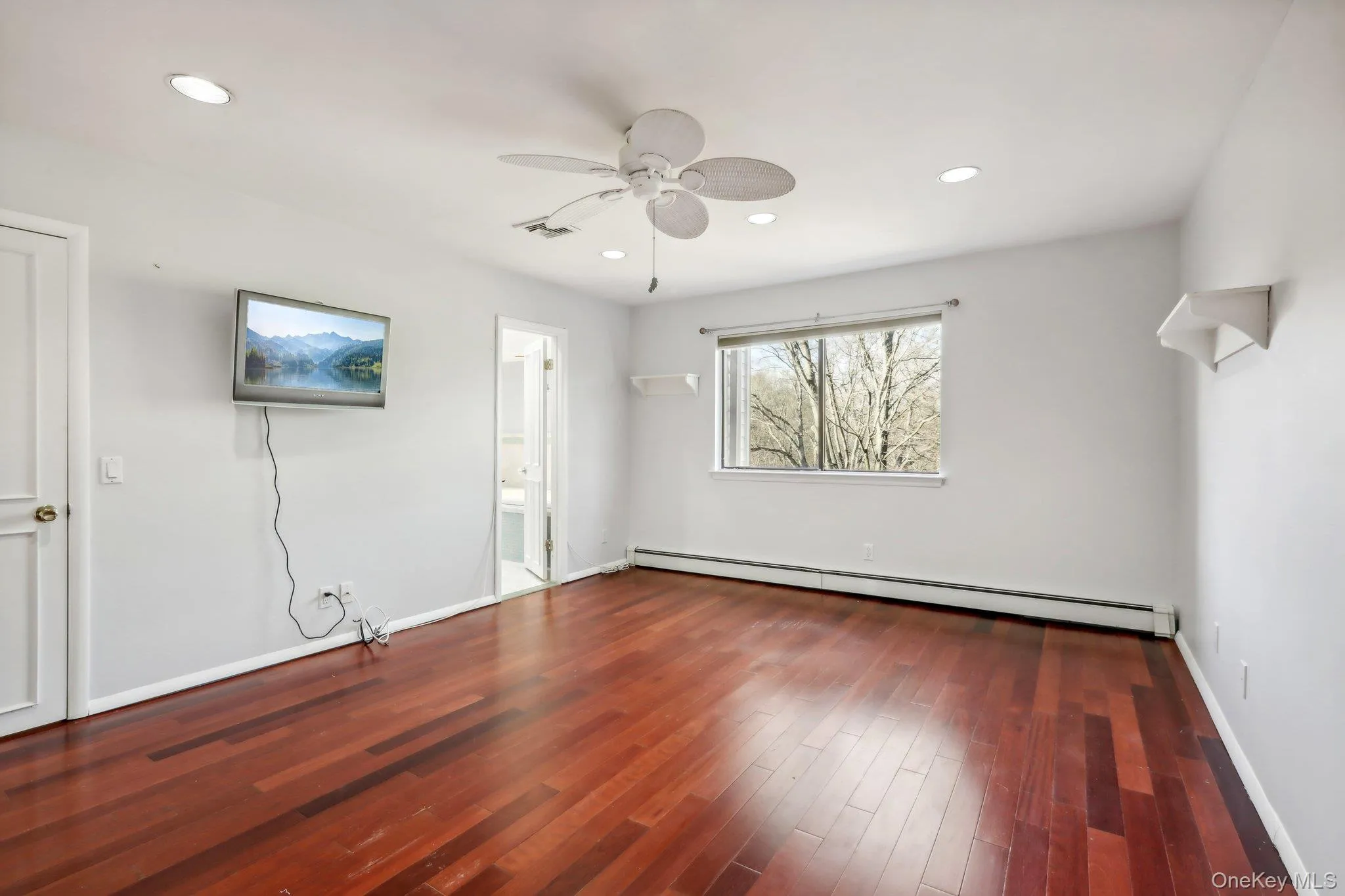 Unfurnished bedroom featuring ceiling fan, a baseboard heating unit, dark wood-style floors, recessed lighting, and connected bathroom Unfurnished bedroom featuring ceiling fan, a baseboard heating unit, dark wood-style floors, recessed lighting, and connected bathroom