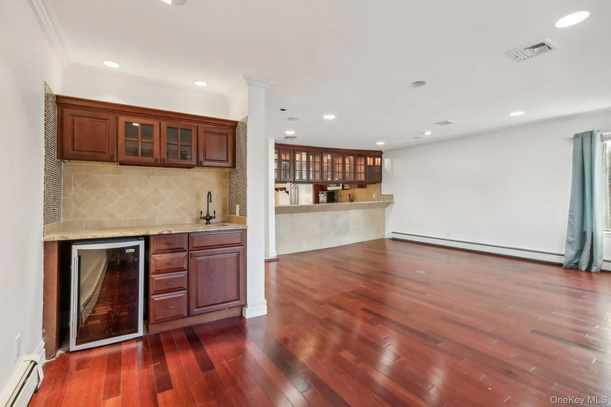 Indoor wet bar featuring wine cooler, tasteful backsplash, light stone countertops, glass insert cabinets, and recessed lighting Indoor wet bar featuring wine cooler, tasteful backsplash, light stone countertops, glass insert cabinets, and recessed lighting