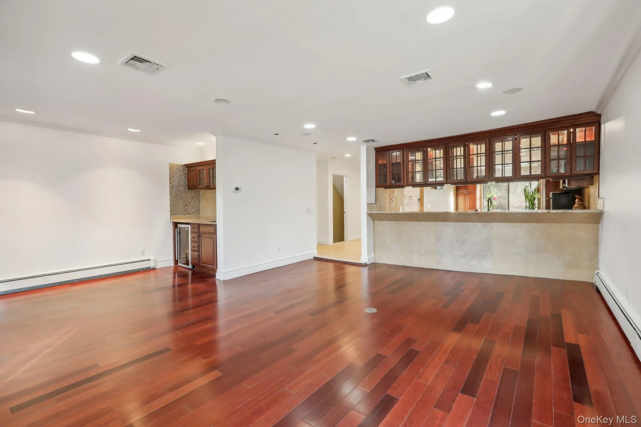 Unfurnished living room with a bar, a baseboard heating unit, dark wood-type flooring, recessed lighting, and beverage cooler Unfurnished living room with a bar, a baseboard heating unit, dark wood-type flooring, recessed lighting, and beverage cooler