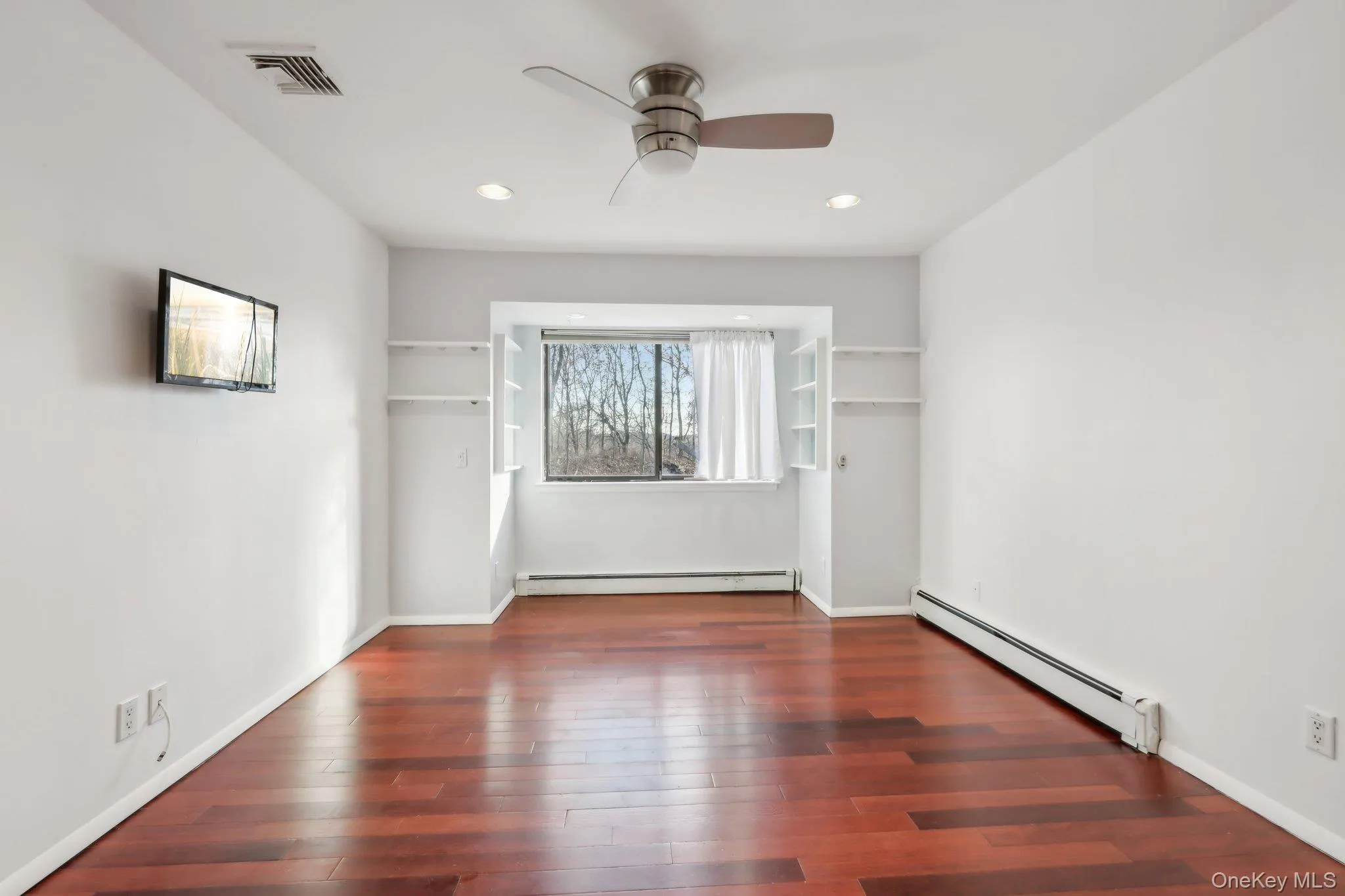 Unfurnished room with baseboard heating, dark wood-type flooring, ceiling fan, and recessed lighting Unfurnished room with baseboard heating, dark wood-type flooring, ceiling fan, and recessed lighting