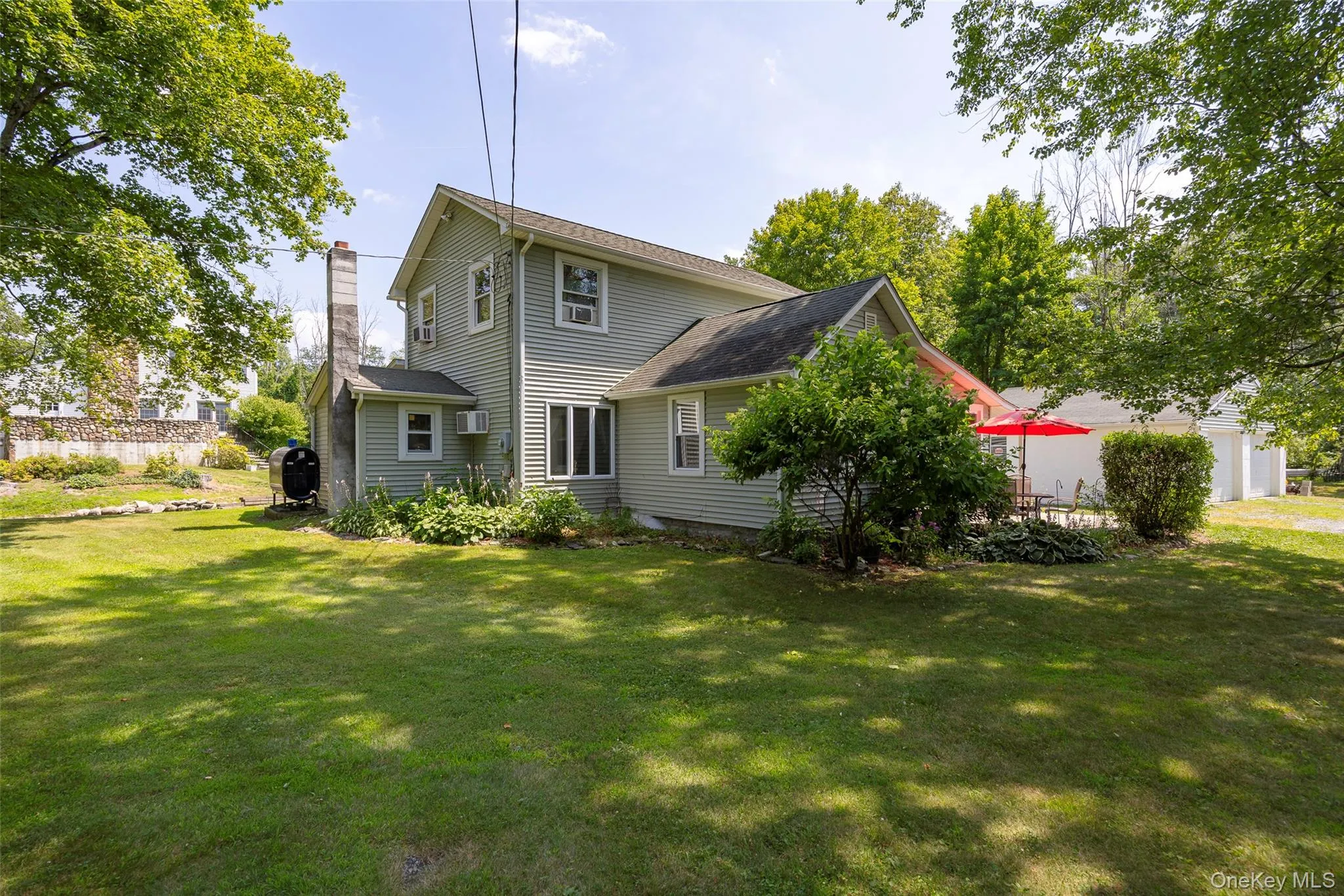 Back of property with a lawn, a chimney, a garage, and a shingled roof Back of property with a lawn, a chimney, a garage, and a shingled roof