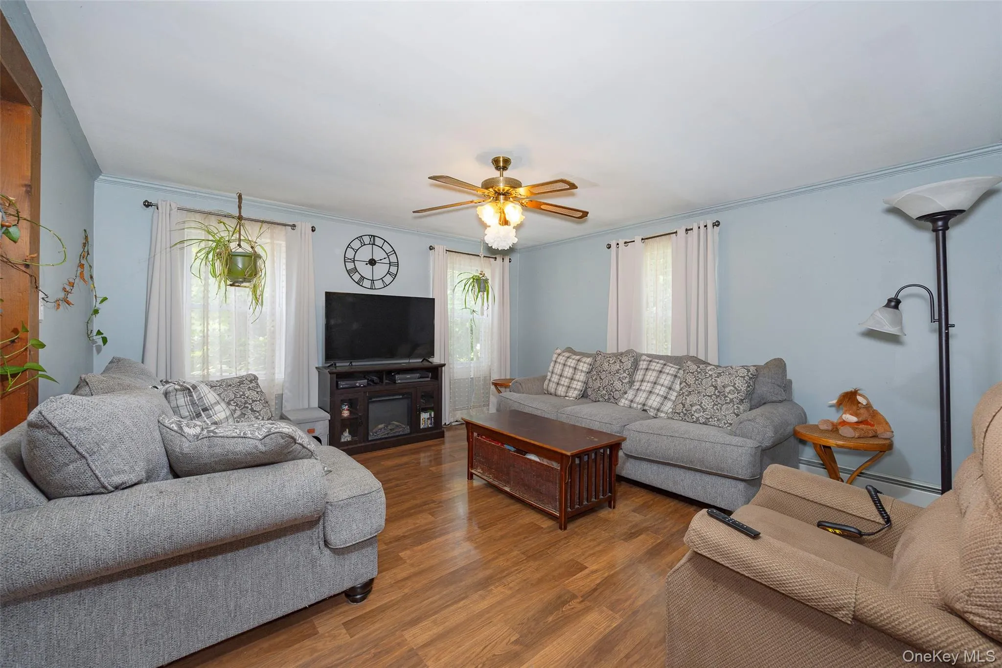 Living area featuring crown molding, wood finished floors, and a ceiling fan Living area featuring crown molding, wood finished floors, and a ceiling fan