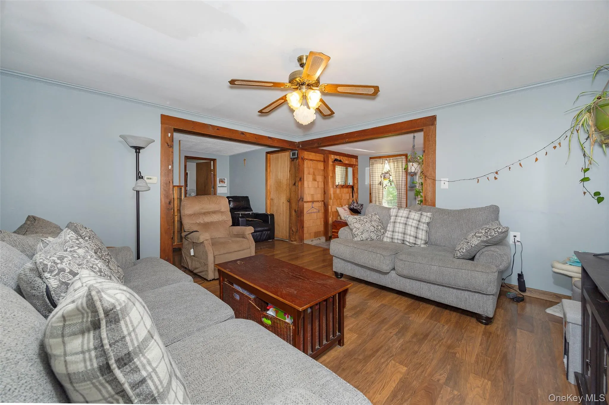 Living room featuring wood finished floors, ornamental molding, and a ceiling fan Living room featuring wood finished floors, ornamental molding, and a ceiling fan