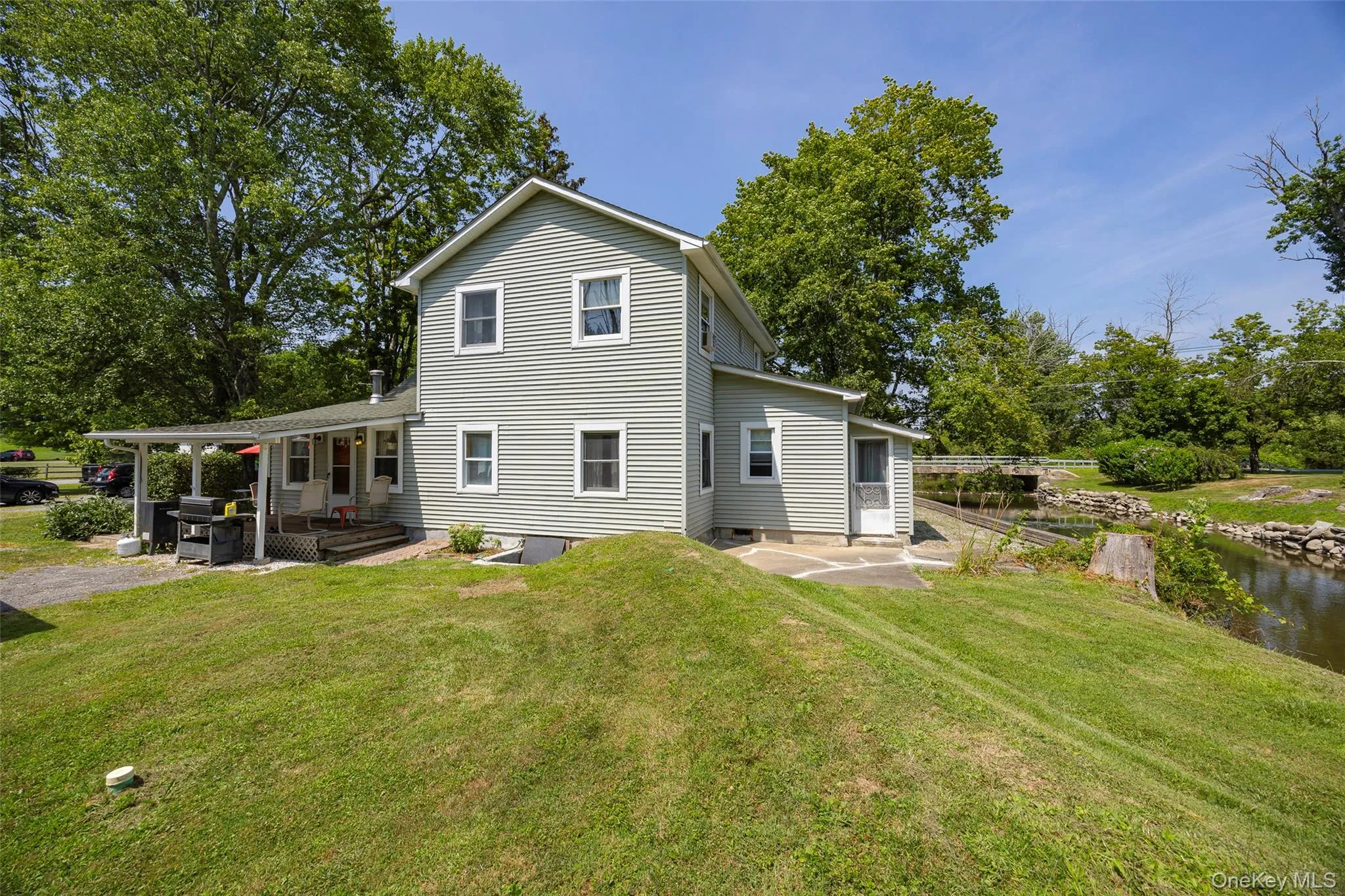 Rear view of property featuring a patio area, a lawn, and a water view Rear view of property featuring a patio area, a lawn, and a water view