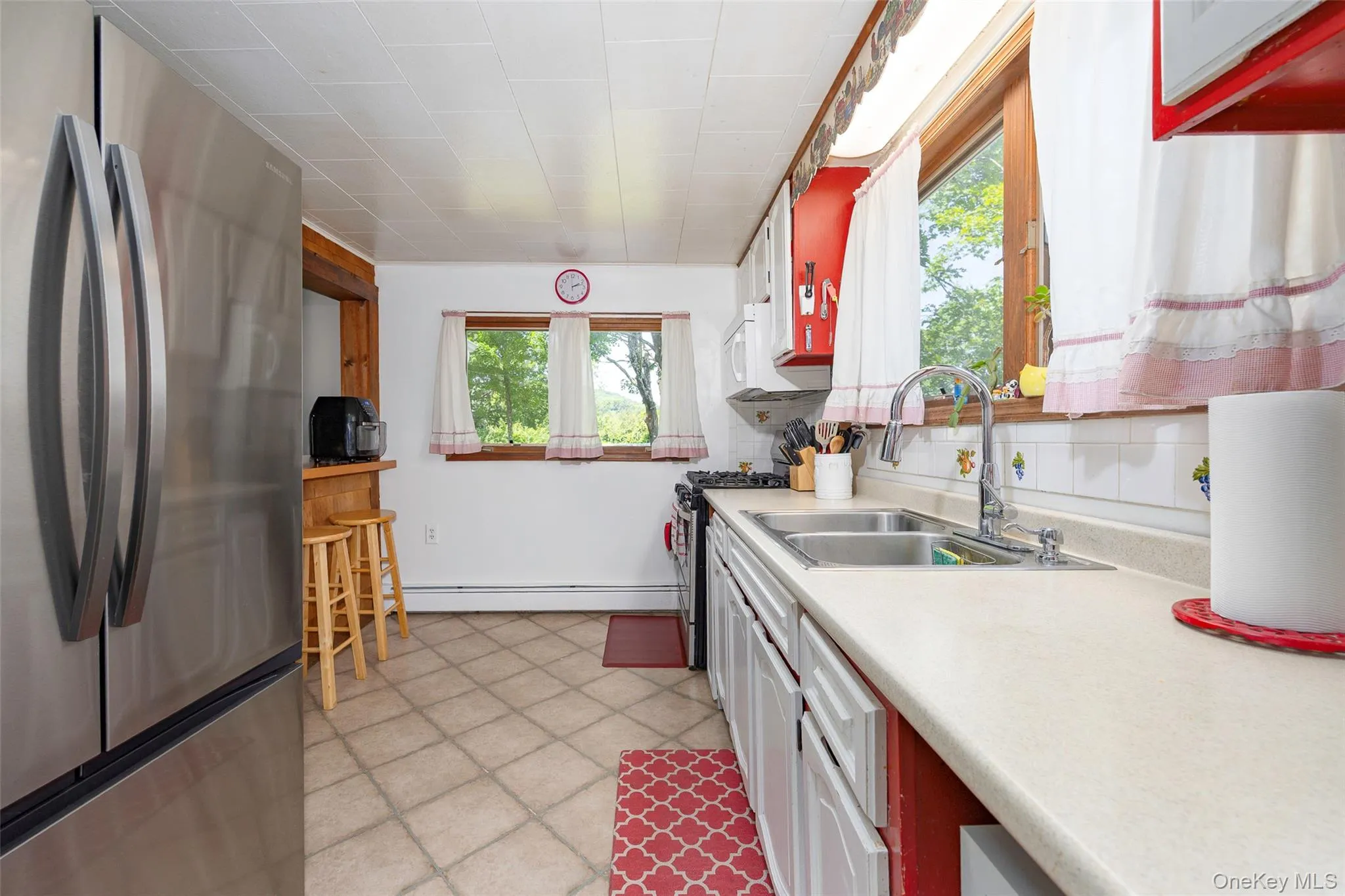 Kitchen with appliances with stainless steel finishes, light countertops, white cabinets, and a baseboard heating unit Kitchen with appliances with stainless steel finishes, light countertops, white cabinets, and a baseboard heating unit