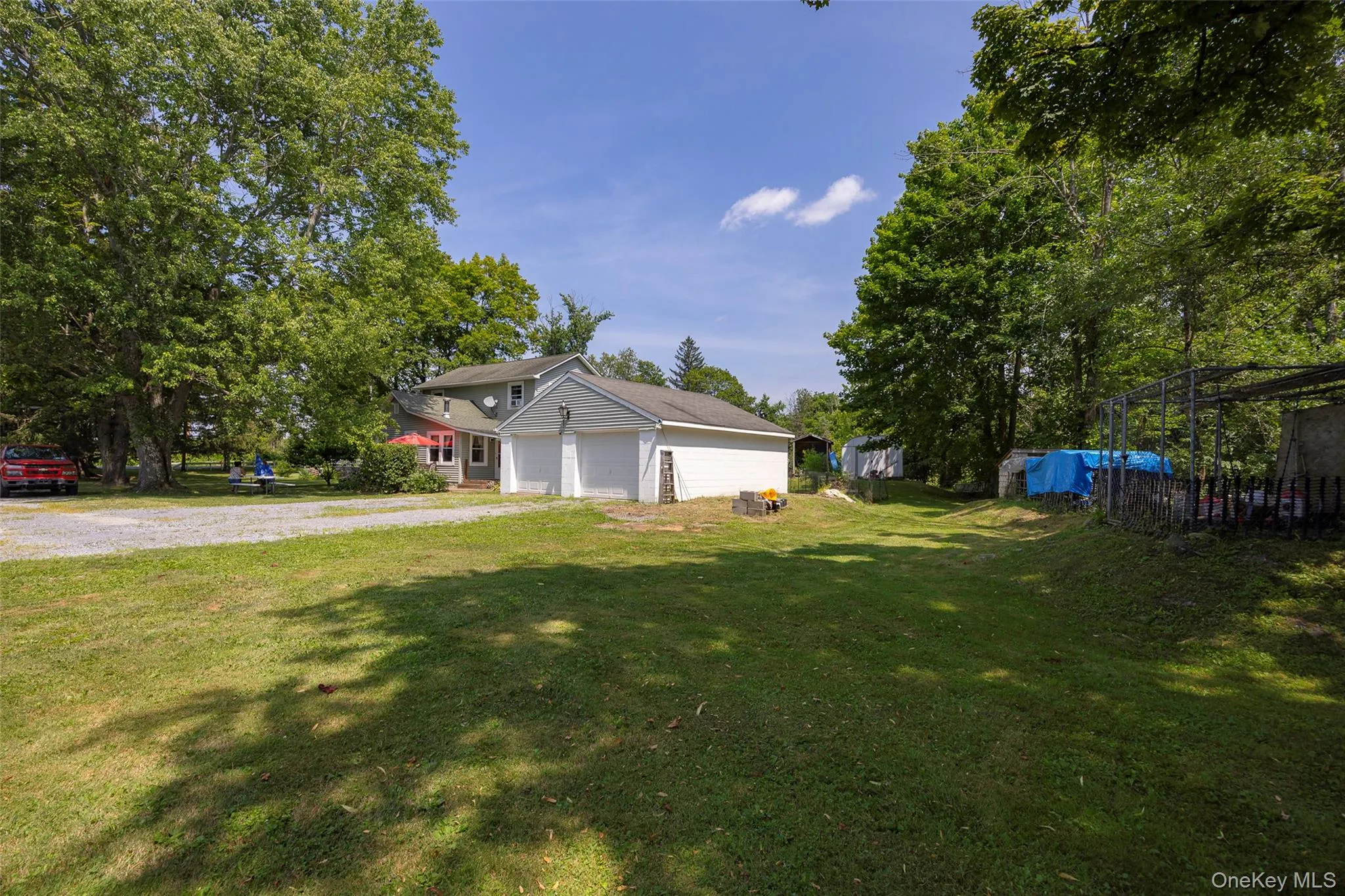 View of front facade featuring driveway, an attached garage, and view of scattered trees View of front facade featuring driveway, an attached garage, and view of scattered trees