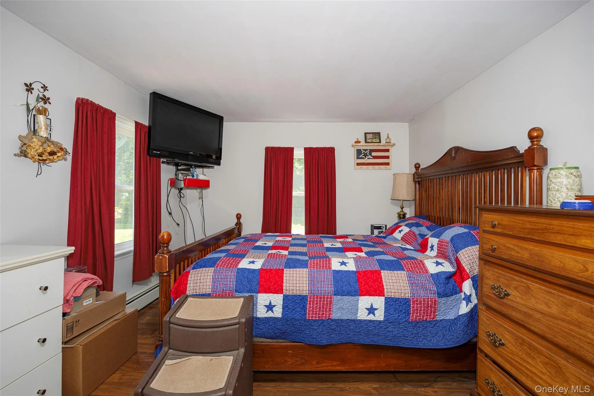 Bedroom featuring wood finished floors and baseboard heating Bedroom featuring wood finished floors and baseboard heating
