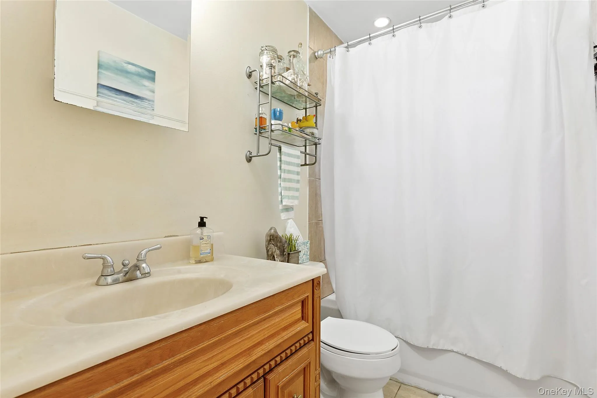 Full bathroom featuring vanity, shower / bathtub combination with curtain, and light tile patterned floors Full bathroom featuring vanity, shower / bathtub combination with curtain, and light tile patterned floors