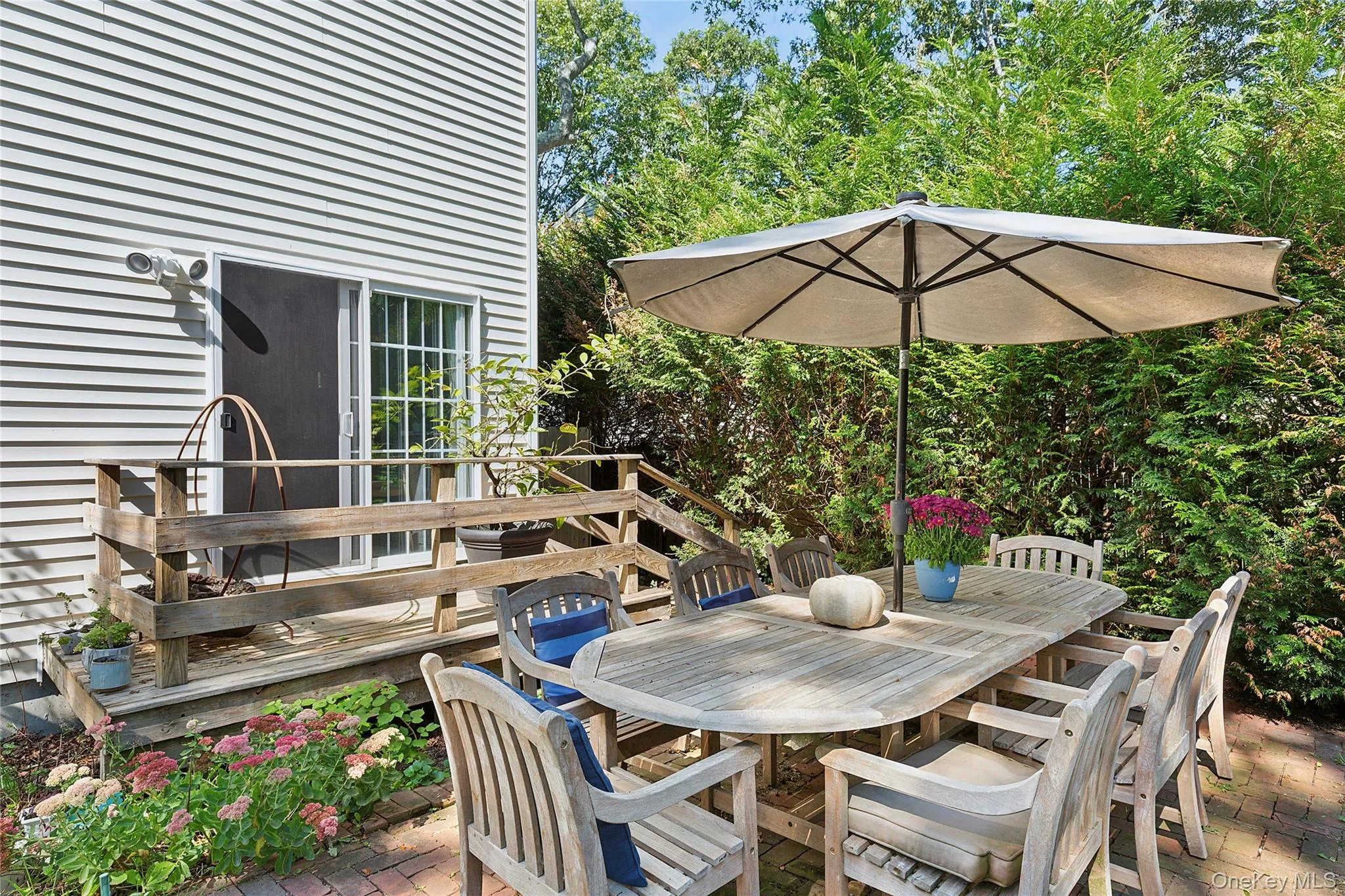 Wooden deck featuring outdoor dining area, a patio area, and view of scattered trees Wooden deck featuring outdoor dining area, a patio area, and view of scattered trees
