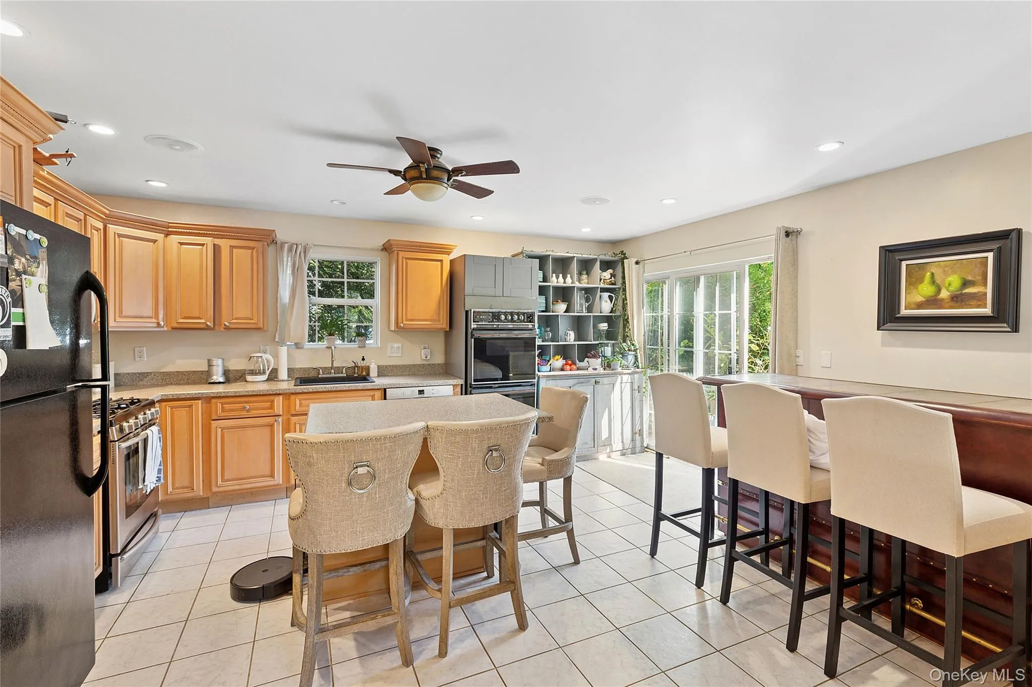 Kitchen featuring black appliances, a breakfast bar area, light tile patterned floors, recessed lighting, and ceiling fan Kitchen featuring black appliances, a breakfast bar area, light tile patterned floors, recessed lighting, and ceiling fan