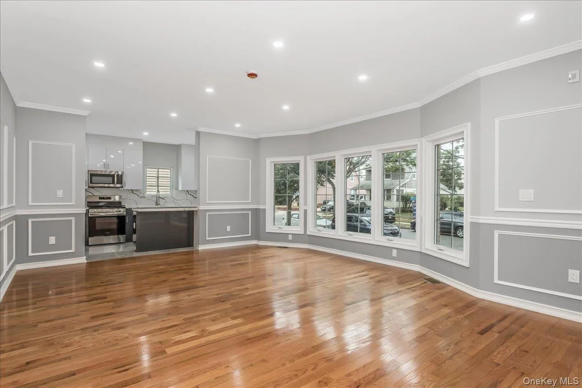 Unfurnished living room with crown molding, a decorative wall, light wood-style floors, and recessed lighting Unfurnished living room with crown molding, a decorative wall, light wood-style floors, and recessed lighting