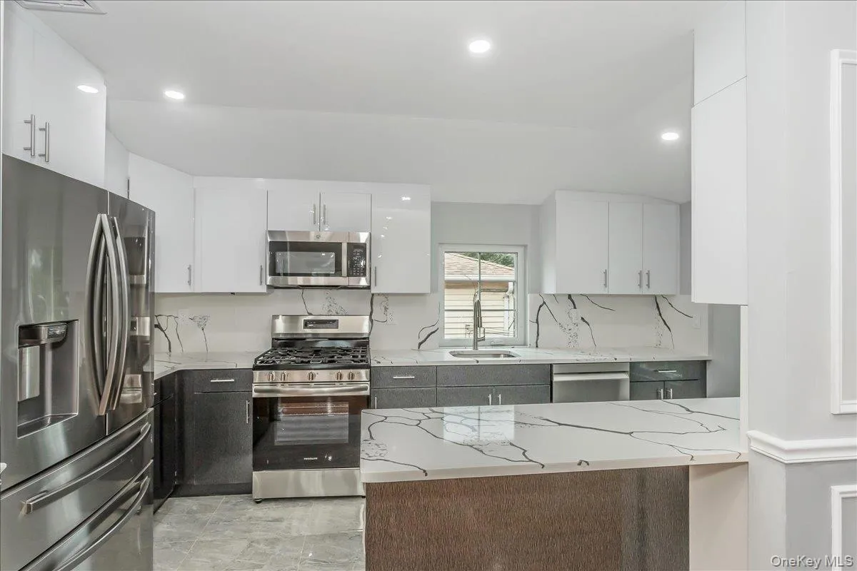 Kitchen with appliances with stainless steel finishes, white cabinetry, light stone counters, and recessed lighting Kitchen with appliances with stainless steel finishes, white cabinetry, light stone counters, and recessed lighting