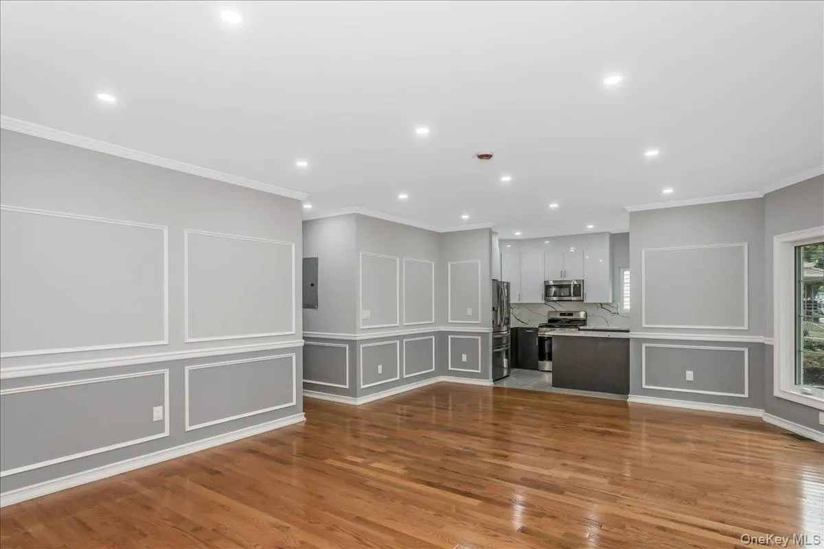 Unfurnished living room with a decorative wall, crown molding, light wood-style flooring, and recessed lighting Unfurnished living room with a decorative wall, crown molding, light wood-style flooring, and recessed lighting