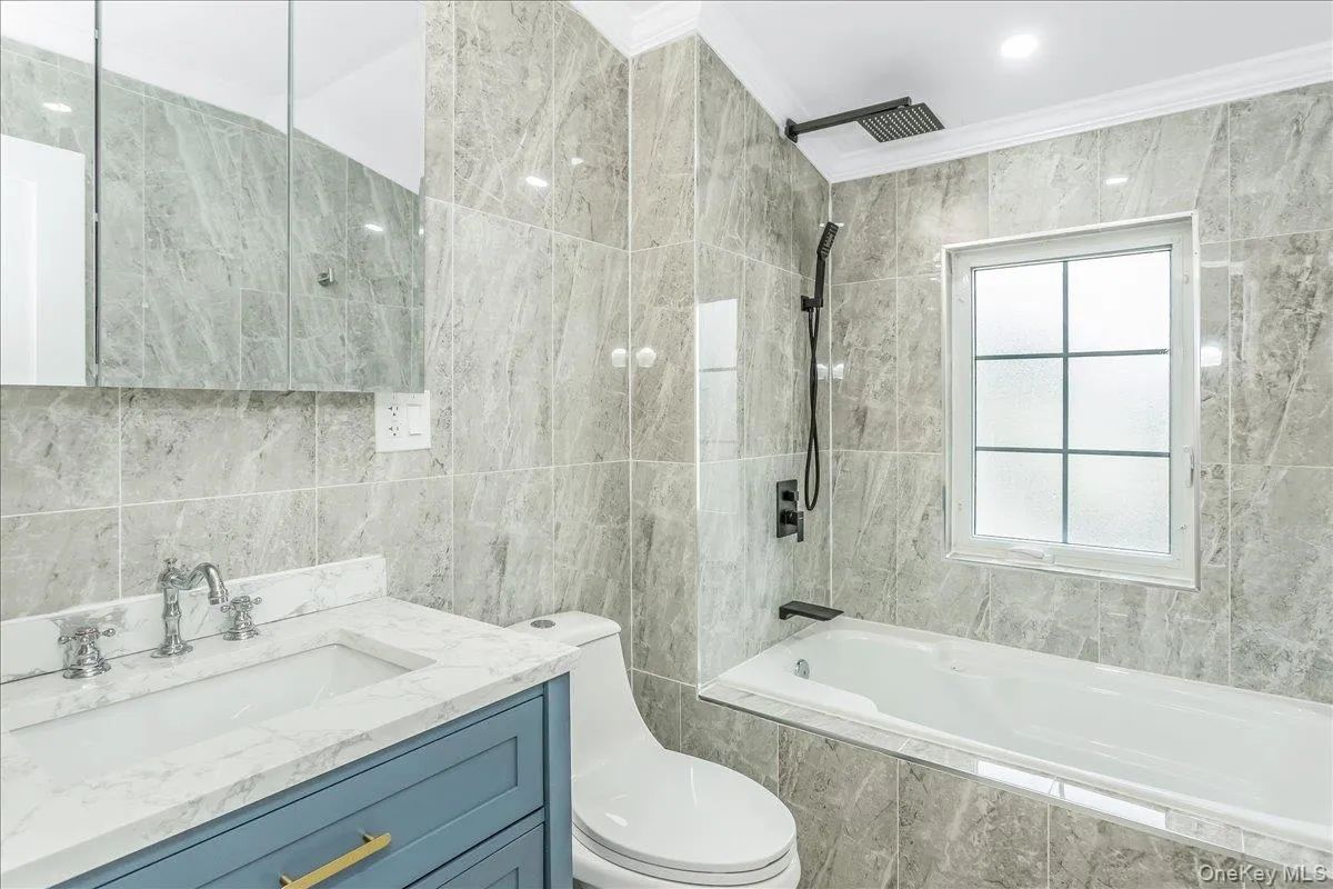 Full bath with tile walls, tiled shower / bath combo, vanity, and crown molding Full bath with tile walls, tiled shower / bath combo, vanity, and crown molding