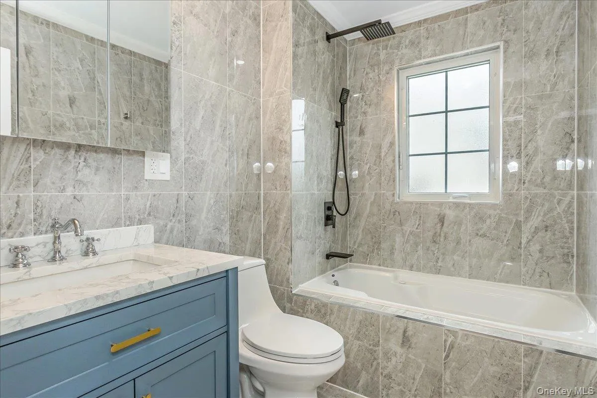 Bathroom with tile walls, tiled shower / bath, and vanity Bathroom with tile walls, tiled shower / bath, and vanity