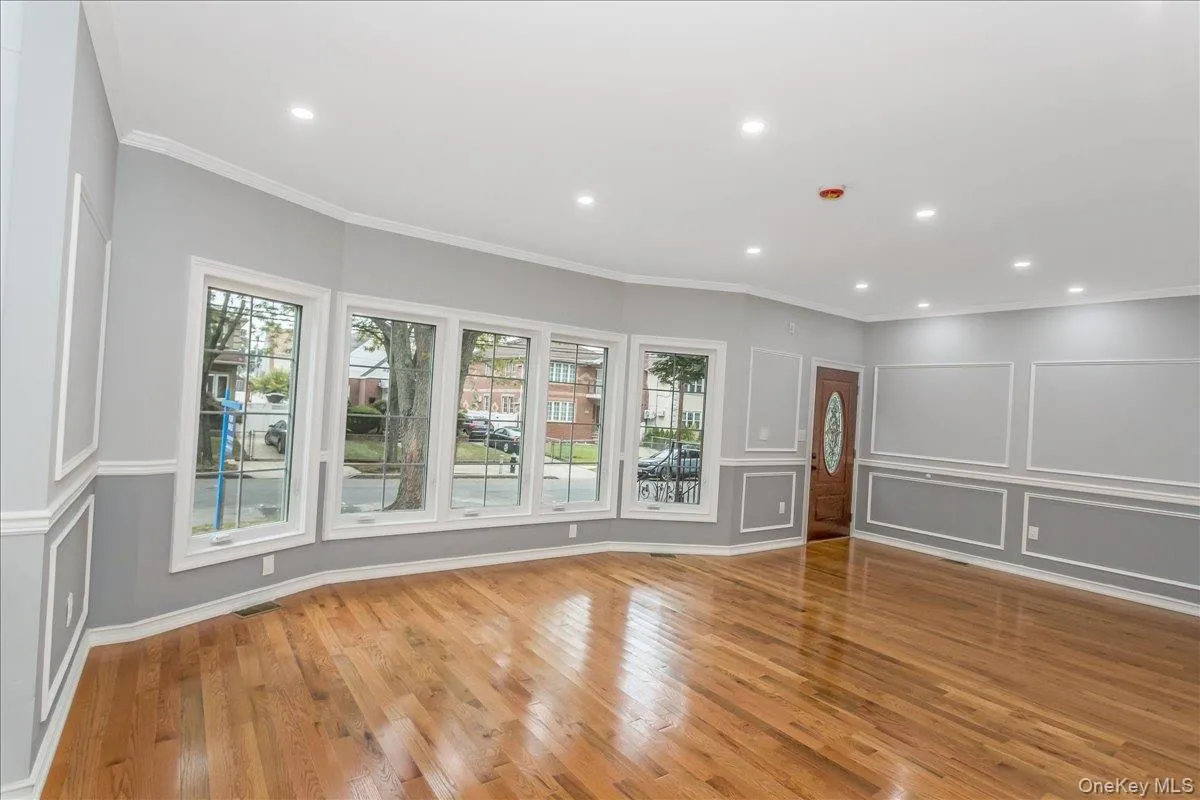 Unfurnished living room featuring crown molding, light wood finished floors, recessed lighting, and a decorative wall Unfurnished living room featuring crown molding, light wood finished floors, recessed lighting, and a decorative wall