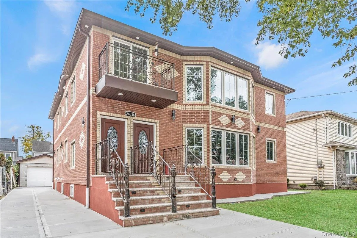 View of front of house with an outdoor structure, brick siding, a garage, a balcony, and a front yard View of front of house with an outdoor structure, brick siding, a garage, a balcony, and a front yard