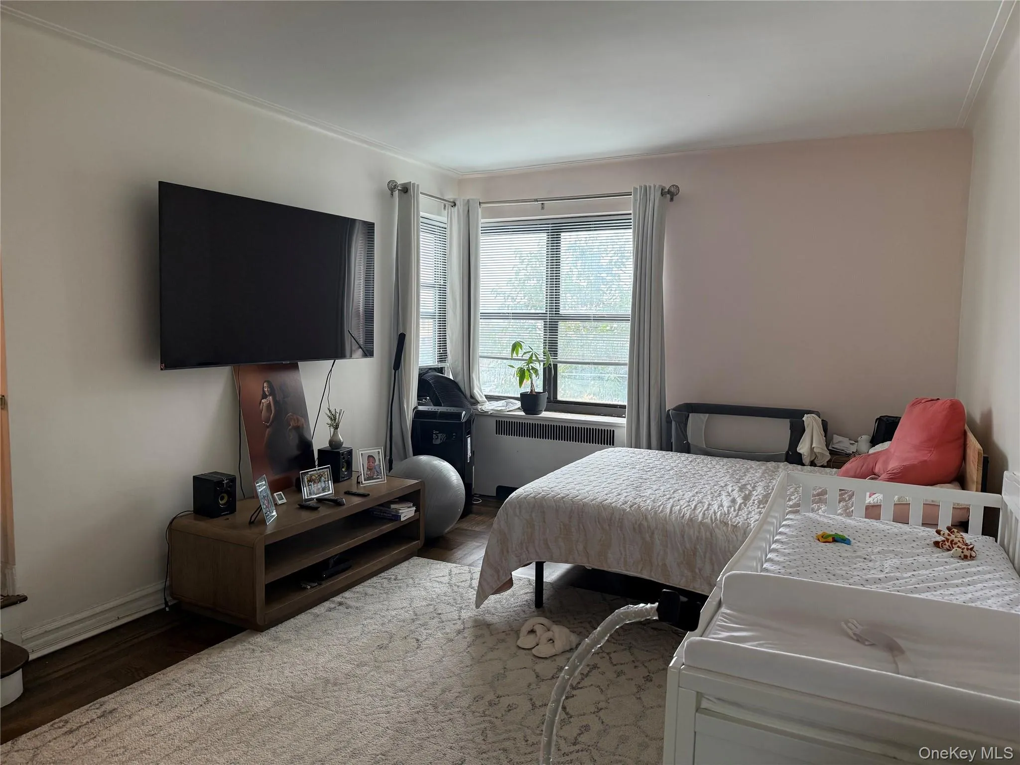 Bedroom with wood finished floors and radiator heating unit Bedroom with wood finished floors and radiator heating unit