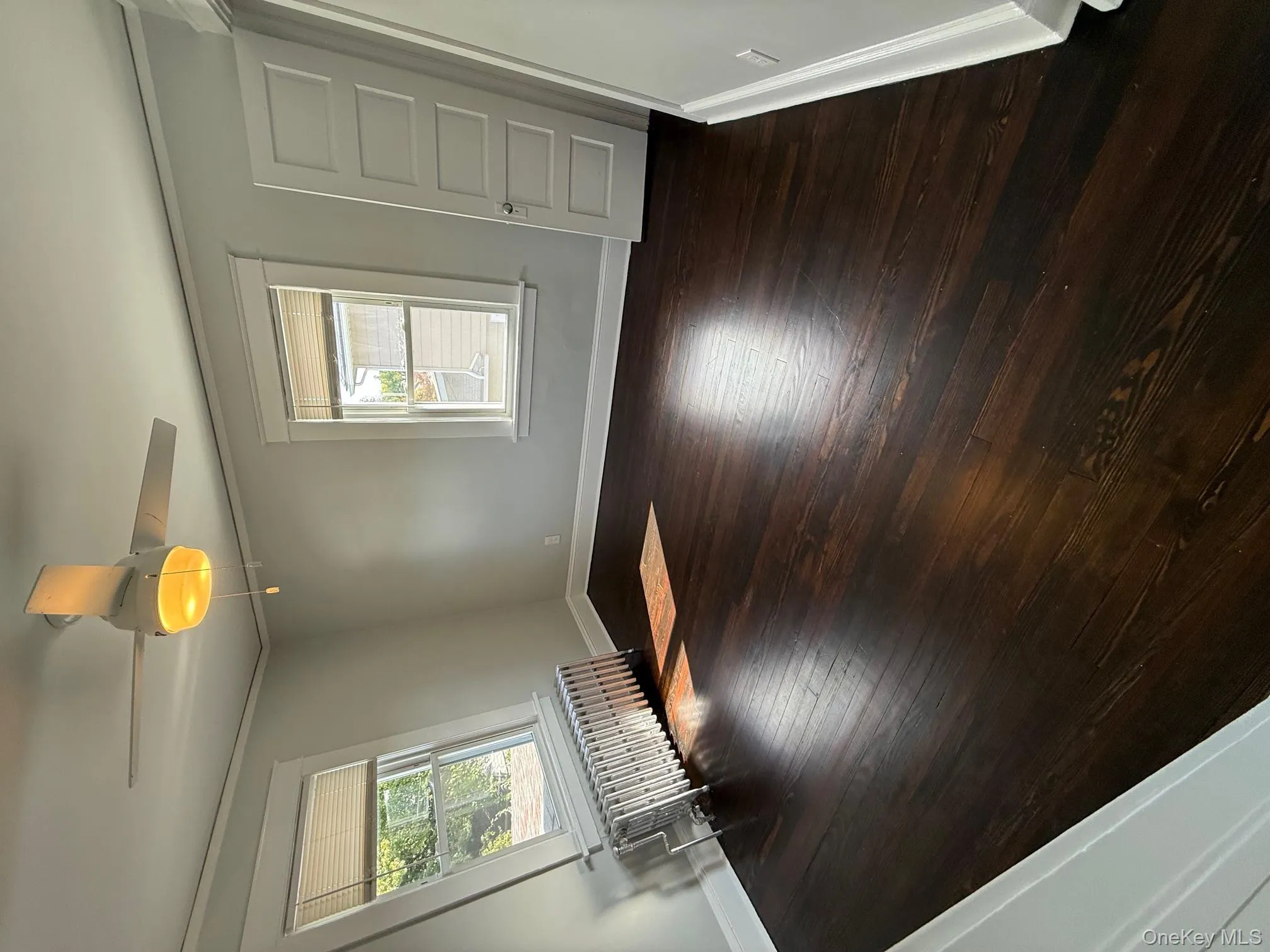 Empty room featuring radiator, ornamental molding, dark wood-type flooring, and ceiling fan Empty room featuring radiator, ornamental molding, dark wood-type flooring, and ceiling fan