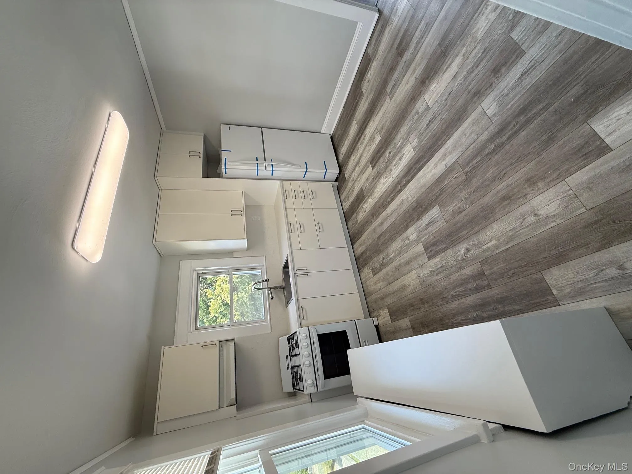 Kitchen featuring white cabinetry, stove, refrigerator, light countertops, and light wood-type flooring Kitchen featuring white cabinetry, stove, refrigerator, light countertops, and light wood-type flooring