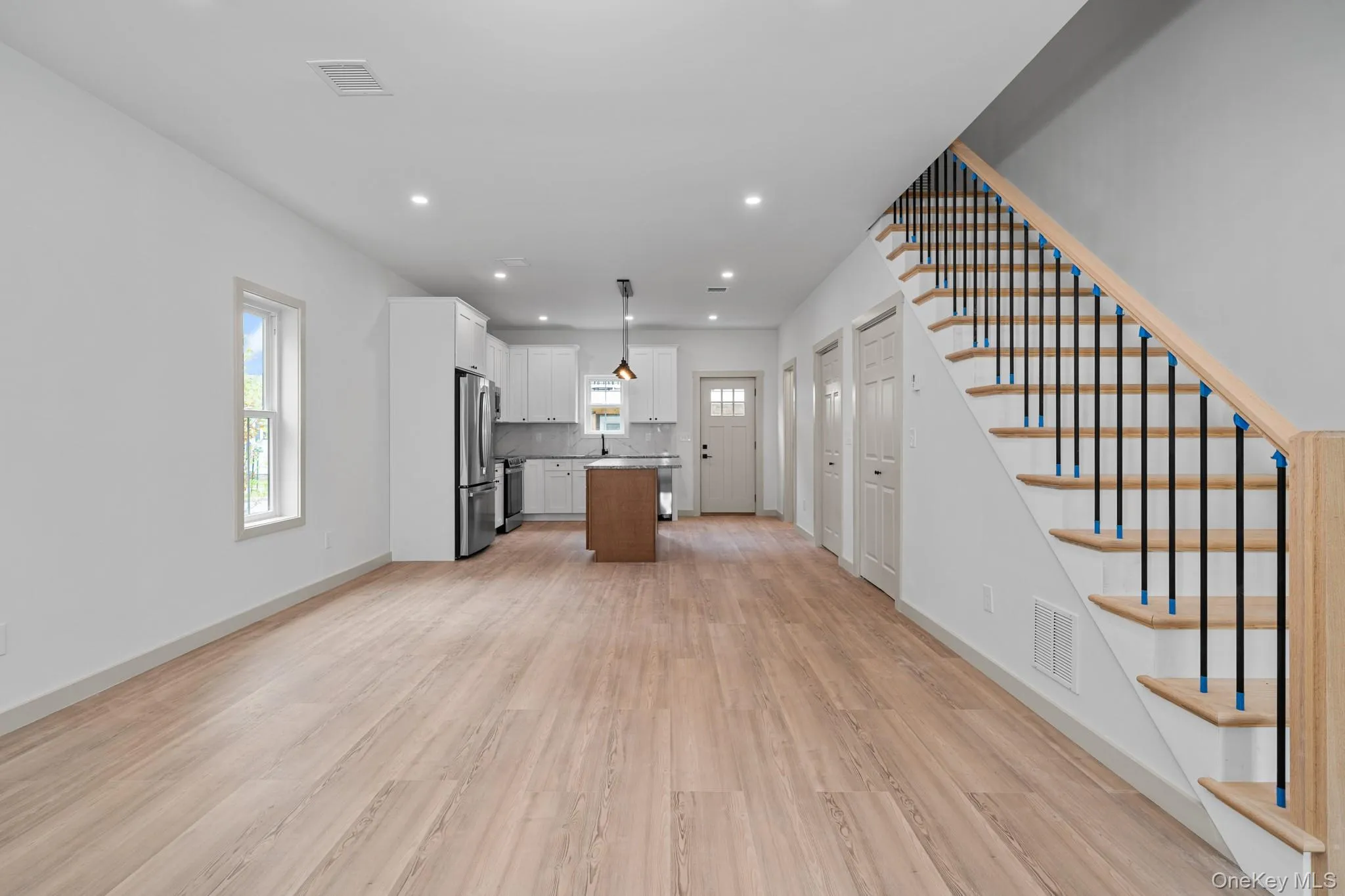 Unfurnished living room featuring light wood finished floors, stairs, recessed lighting, and plenty of natural light Unfurnished living room featuring light wood finished floors, stairs, recessed lighting, and plenty of natural light