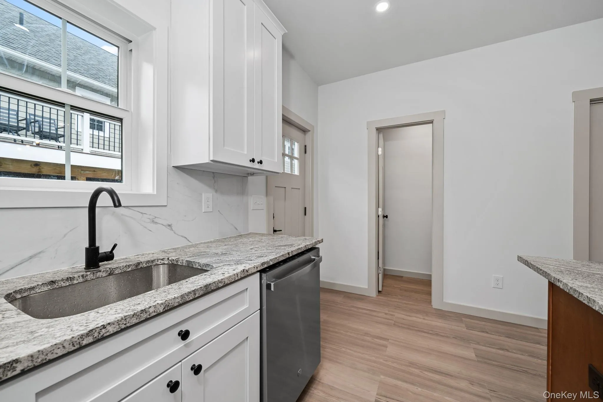 Kitchen featuring plenty of natural light, dishwasher, light wood-style flooring, light stone counters, and recessed lighting Kitchen featuring plenty of natural light, dishwasher, light wood-style flooring, light stone counters, and recessed lighting