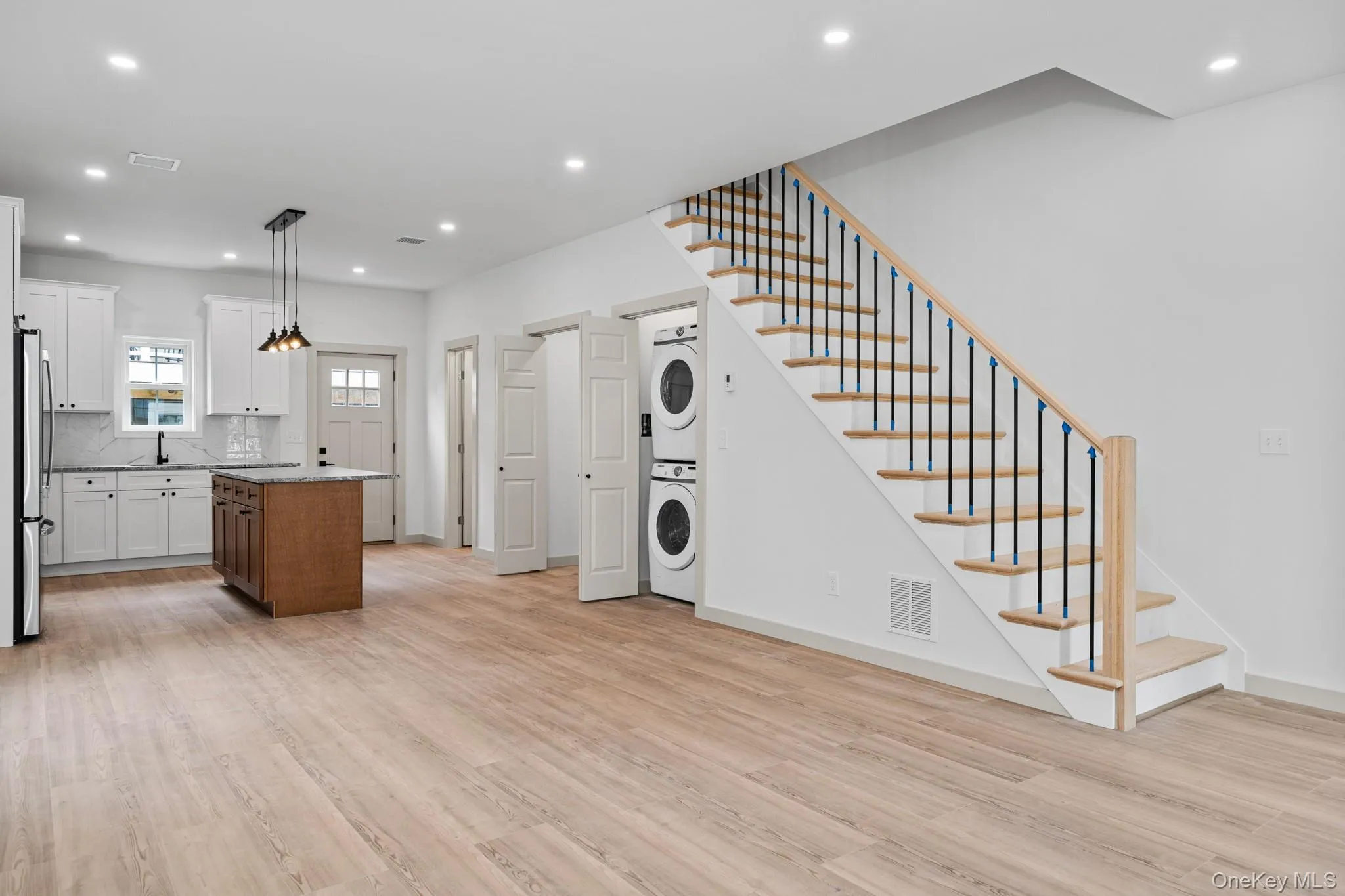 Kitchen featuring light wood finished floors, white cabinetry, recessed lighting, tasteful backsplash, and hanging light fixtures Kitchen featuring light wood finished floors, white cabinetry, recessed lighting, tasteful backsplash, and hanging light fixtures