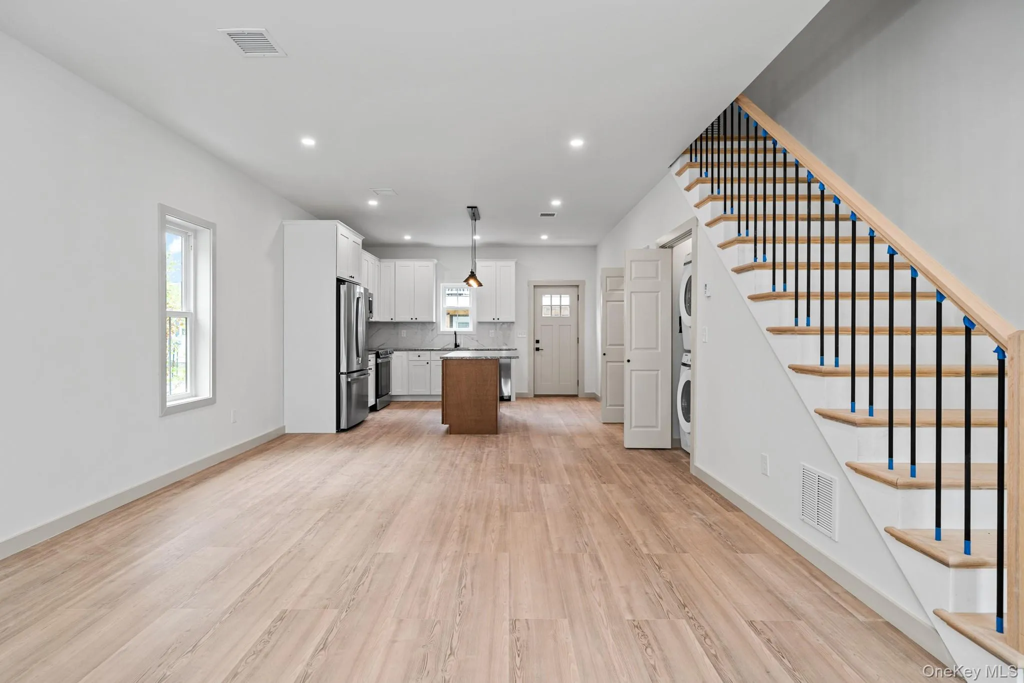 Kitchen featuring a center island, open floor plan, light wood-style flooring, white cabinets, and recessed lighting Kitchen featuring a center island, open floor plan, light wood-style flooring, white cabinets, and recessed lighting