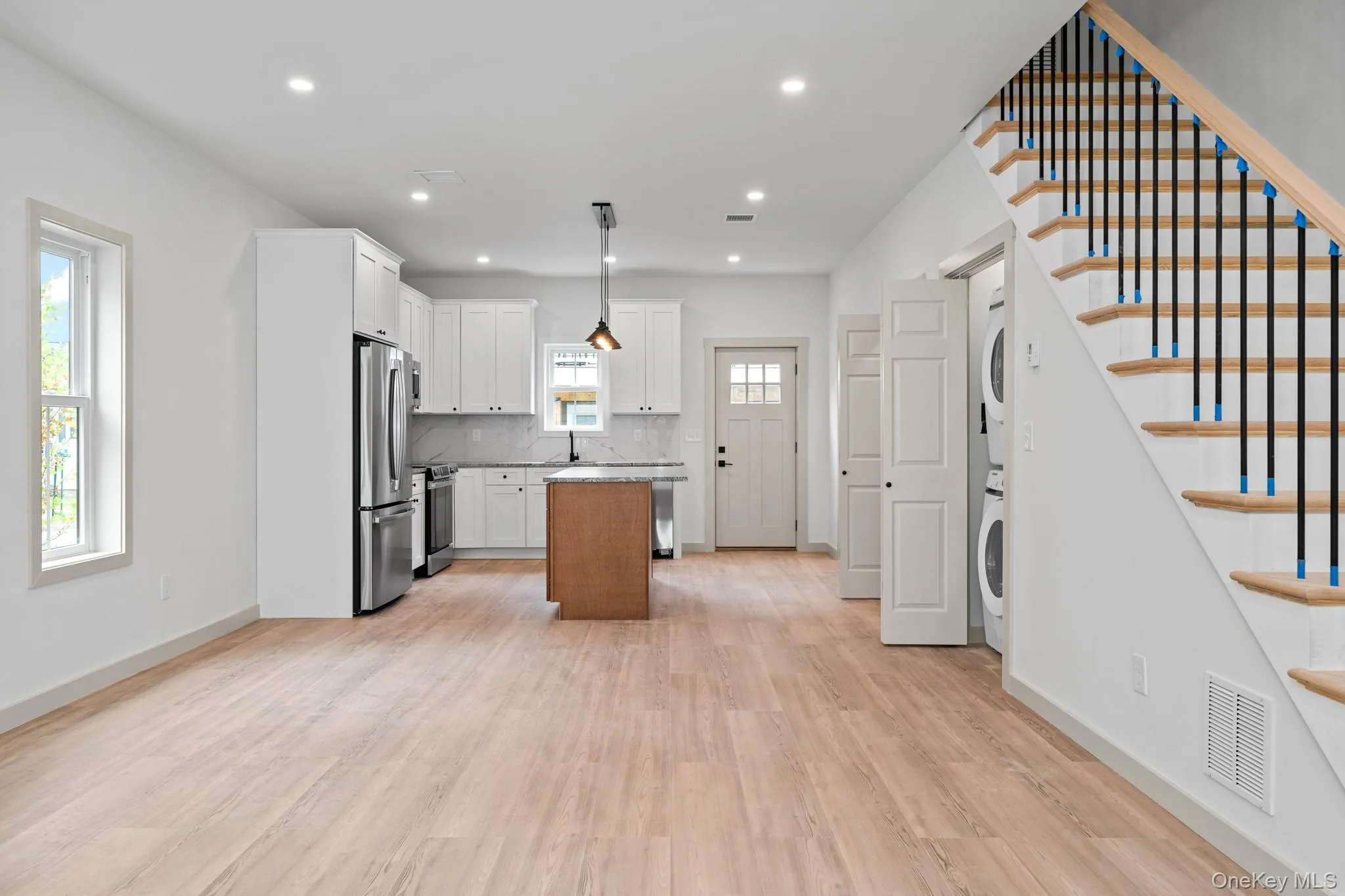Kitchen with a center island, light wood-style flooring, white cabinetry, tasteful backsplash, and stainless steel appliances Kitchen with a center island, light wood-style flooring, white cabinetry, tasteful backsplash, and stainless steel appliances
