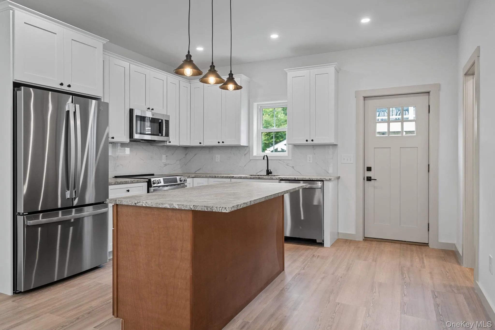 Kitchen featuring stainless steel appliances, backsplash, pendant lighting, a kitchen island, and recessed lighting Kitchen featuring stainless steel appliances, backsplash, pendant lighting, a kitchen island, and recessed lighting