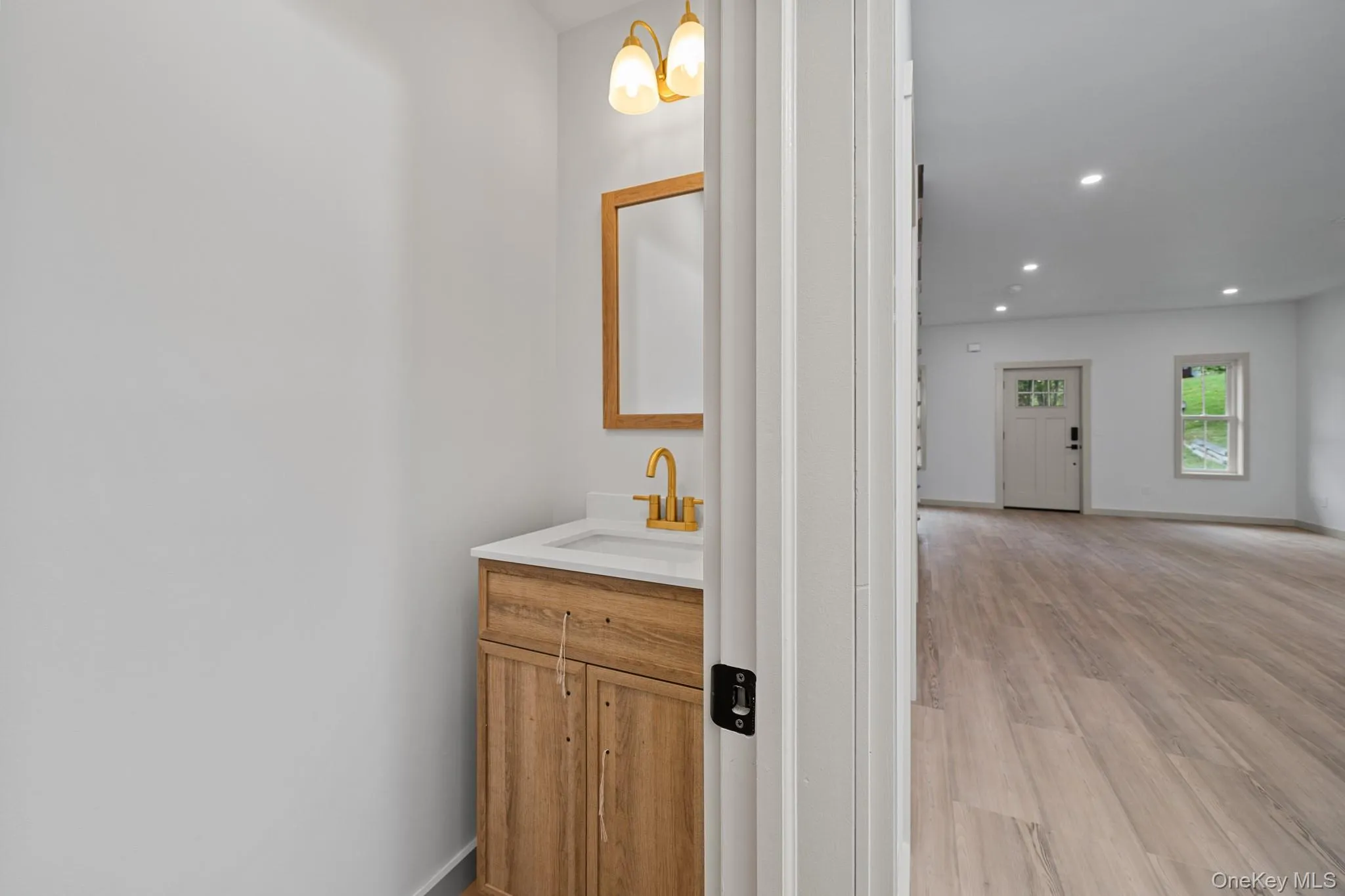 Half bath featuring vanity, recessed lighting, and light wood-style floors Half bath featuring vanity, recessed lighting, and light wood-style floors