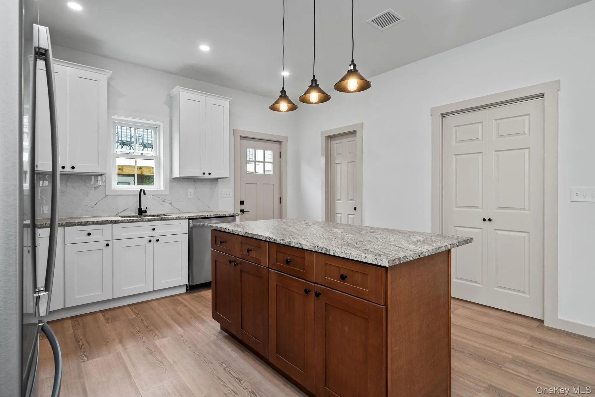 Kitchen with white cabinetry, stainless steel appliances, decorative light fixtures, decorative backsplash, and recessed lighting Kitchen with white cabinetry, stainless steel appliances, decorative light fixtures, decorative backsplash, and recessed lighting