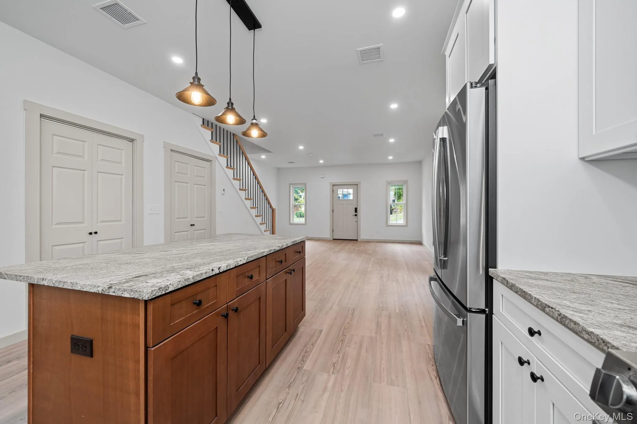 Kitchen featuring light stone counters, a kitchen island, freestanding refrigerator, recessed lighting, and pendant lighting Kitchen featuring light stone counters, a kitchen island, freestanding refrigerator, recessed lighting, and pendant lighting