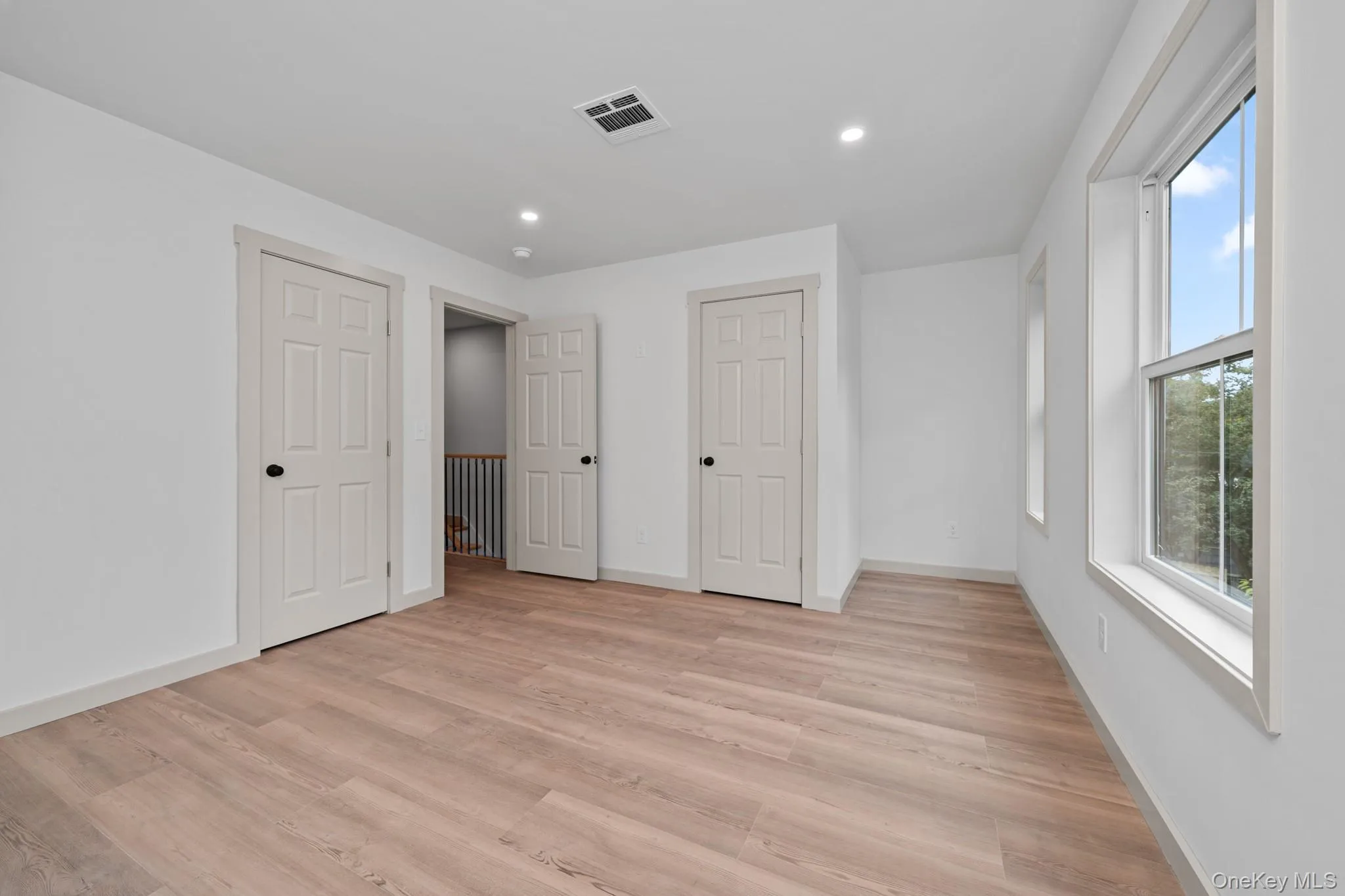 Unfurnished bedroom featuring light wood-type flooring, recessed lighting, and two closets Unfurnished bedroom featuring light wood-type flooring, recessed lighting, and two closets