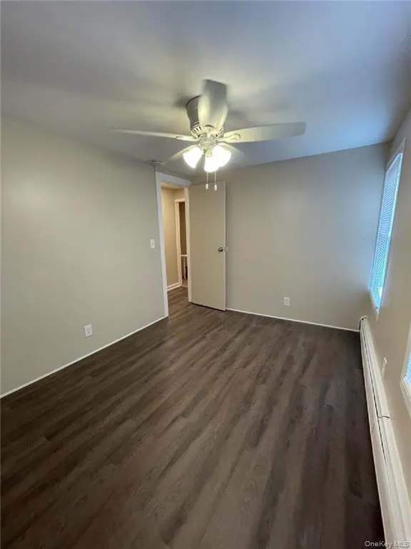 Spare room with dark wood-style flooring, baseboard heating, and a ceiling fan Spare room with dark wood-style flooring, baseboard heating, and a ceiling fan