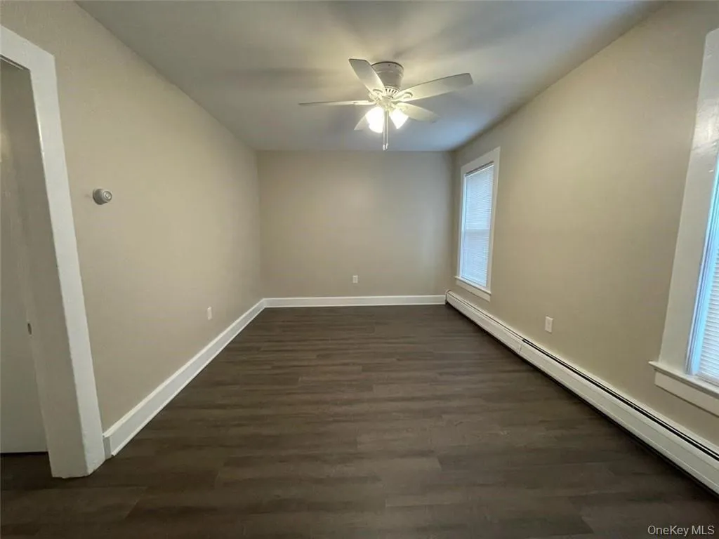 Spare room with baseboard heating, dark wood finished floors, and ceiling fan Spare room with baseboard heating, dark wood finished floors, and ceiling fan