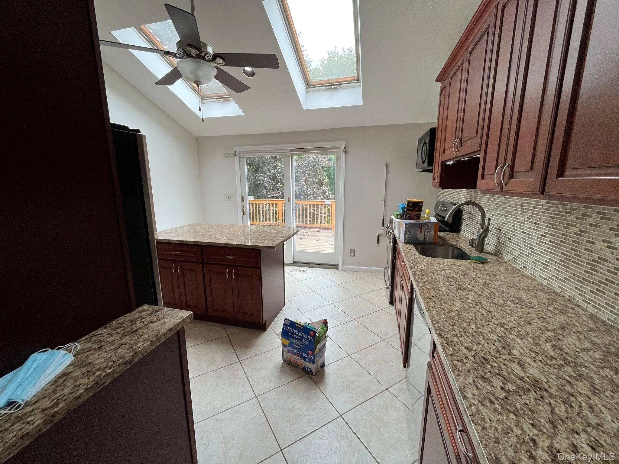Kitchen featuring light tile patterned floors, dark brown cabinetry, lofted ceiling, stainless steel appliances, and decorative backsplash Kitchen featuring light tile patterned floors, dark brown cabinetry, lofted ceiling, stainless steel appliances, and decorative backsplash