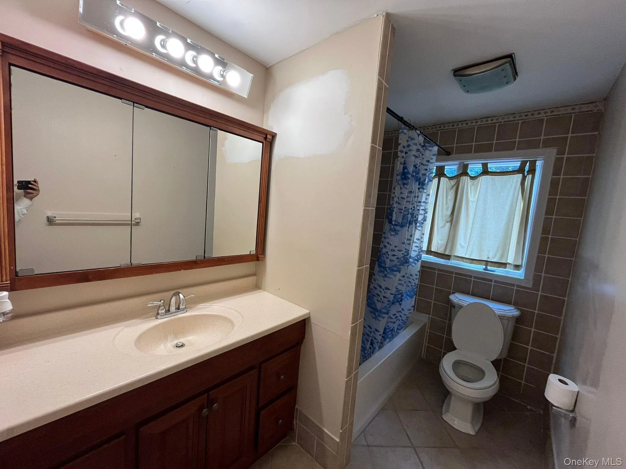 Bathroom with light tile patterned floors, shower / tub combo with curtain, and vanity Bathroom with light tile patterned floors, shower / tub combo with curtain, and vanity