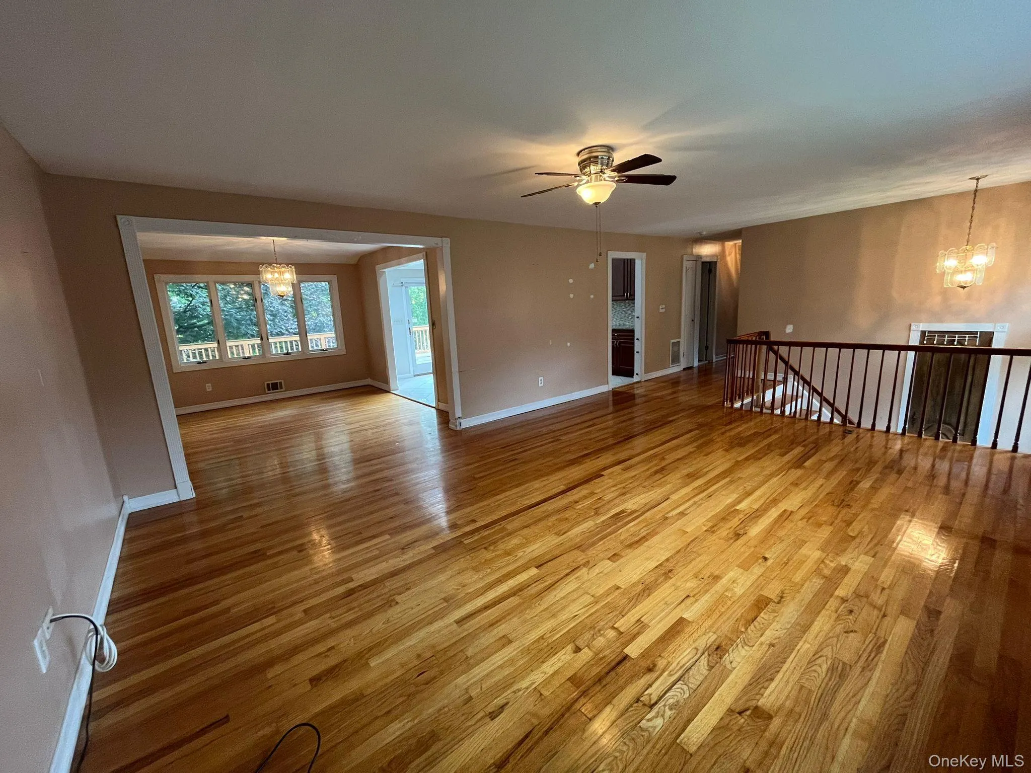 Unfurnished room with a chandelier, light wood-style floors, and a ceiling fan Unfurnished room with a chandelier, light wood-style floors, and a ceiling fan