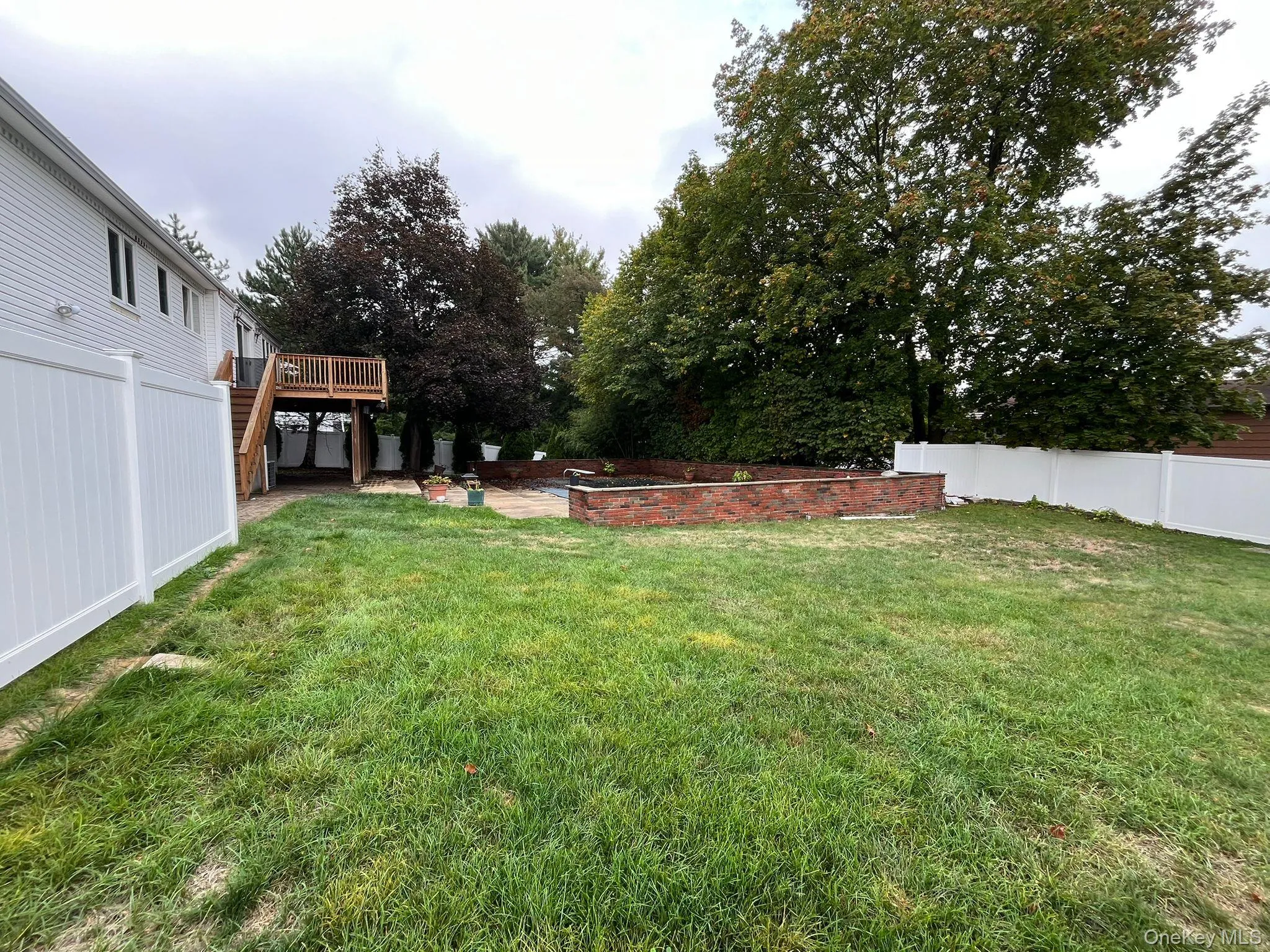 Fenced backyard featuring a patio area, a deck, and stairway Fenced backyard featuring a patio area, a deck, and stairway