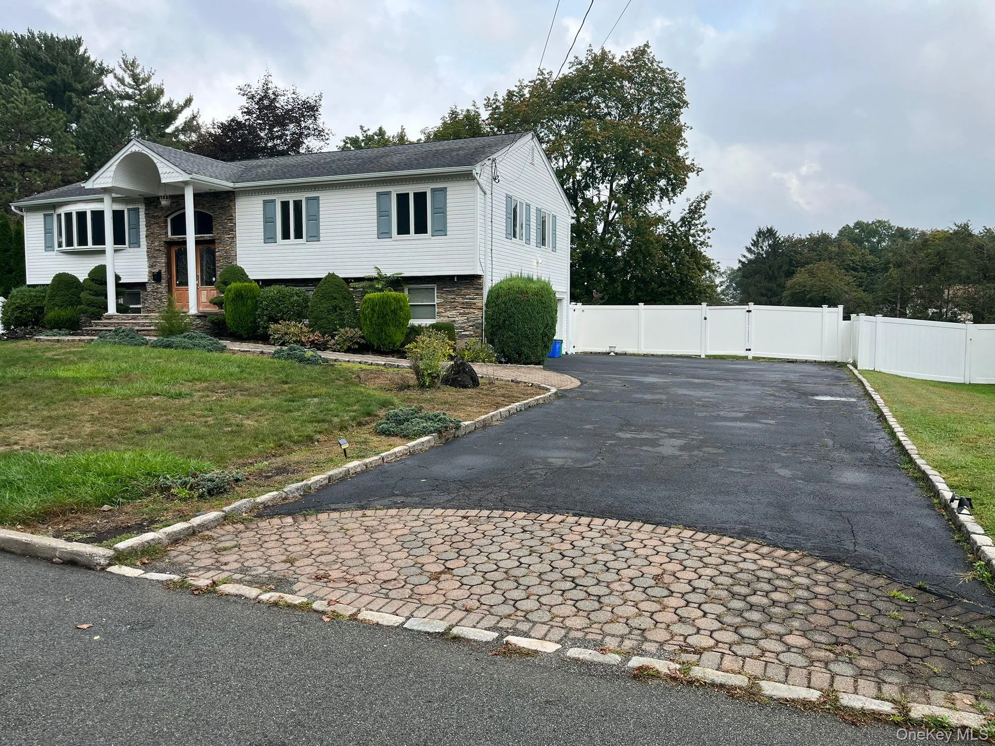 View of front facade featuring asphalt driveway, a gate, and stone siding View of front facade featuring asphalt driveway, a gate, and stone siding