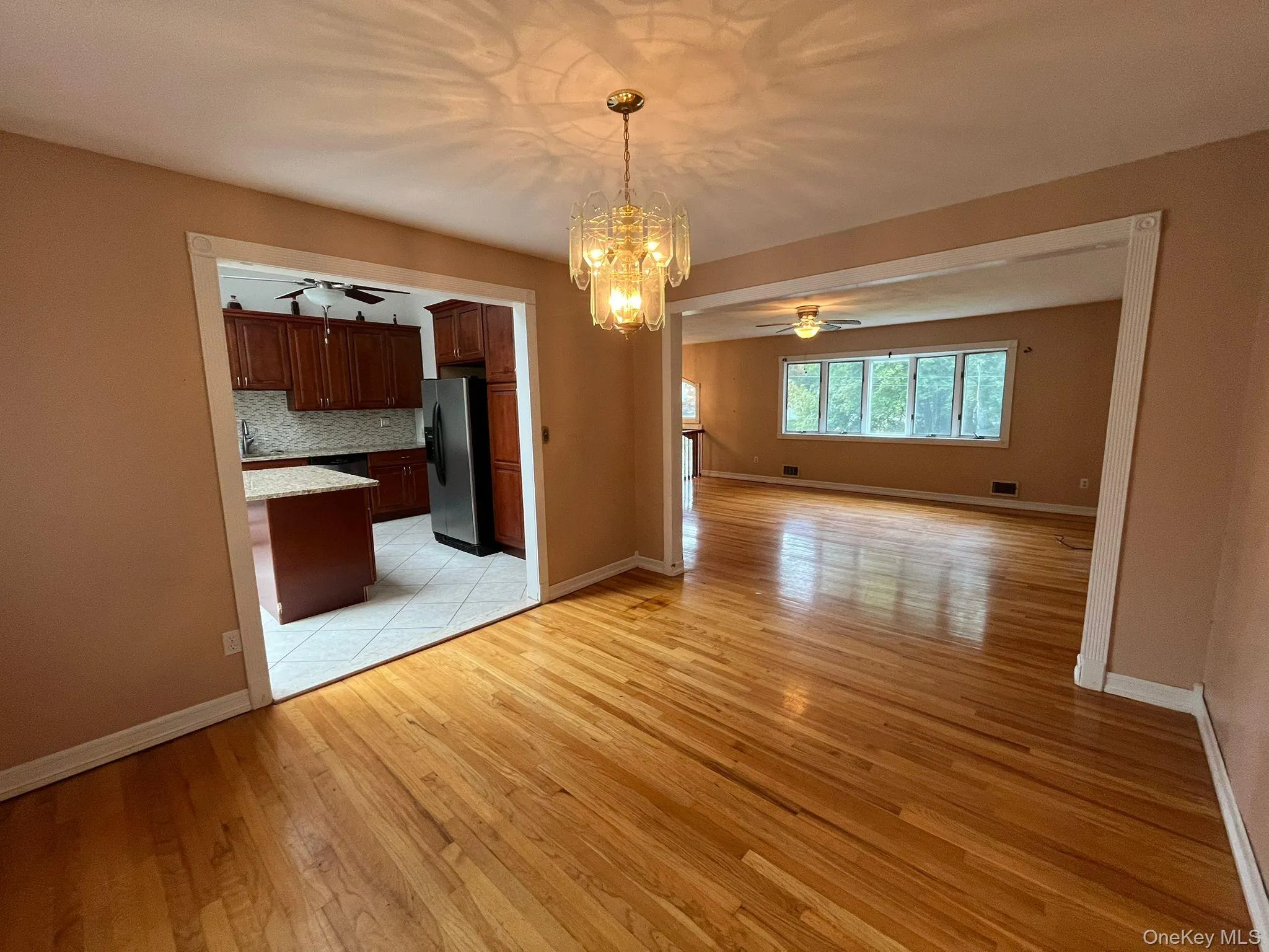 Unfurnished dining area with a ceiling fan, a chandelier, and light wood-style flooring Unfurnished dining area with a ceiling fan, a chandelier, and light wood-style flooring
