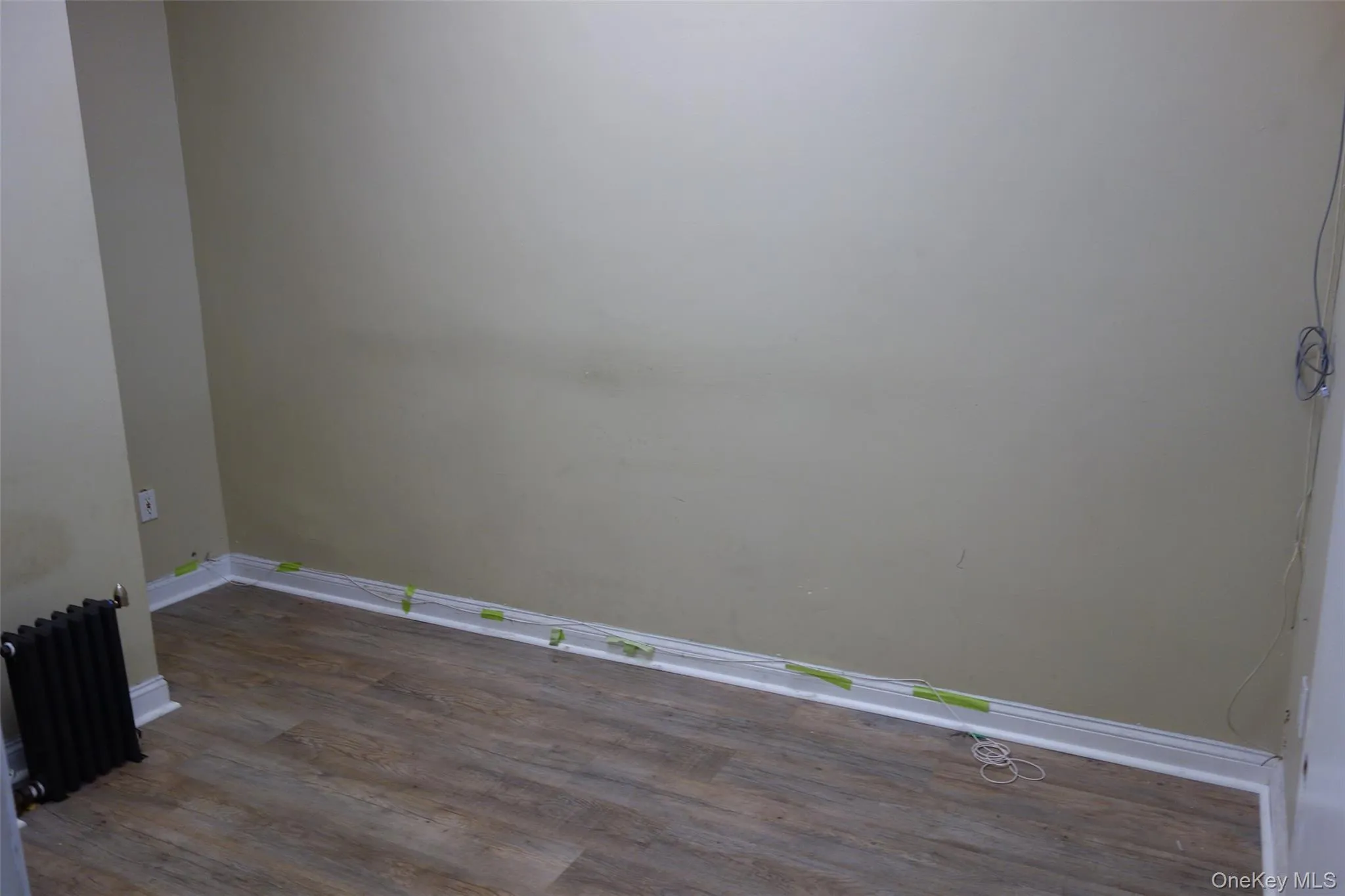 Unfurnished room featuring radiator and dark wood-type flooring Unfurnished room featuring radiator and dark wood-type flooring