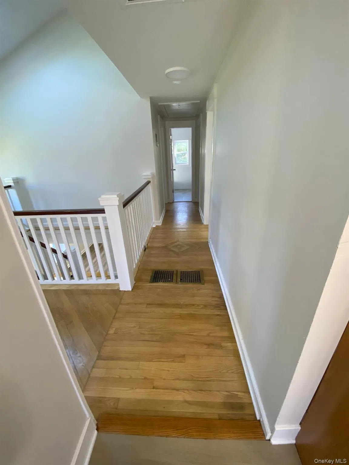 Corridor featuring light wood finished floors and an upstairs landing Corridor featuring light wood finished floors and an upstairs landing
