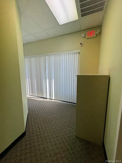 Corridor with dark colored carpet and a paneled ceiling Corridor with dark colored carpet and a paneled ceiling