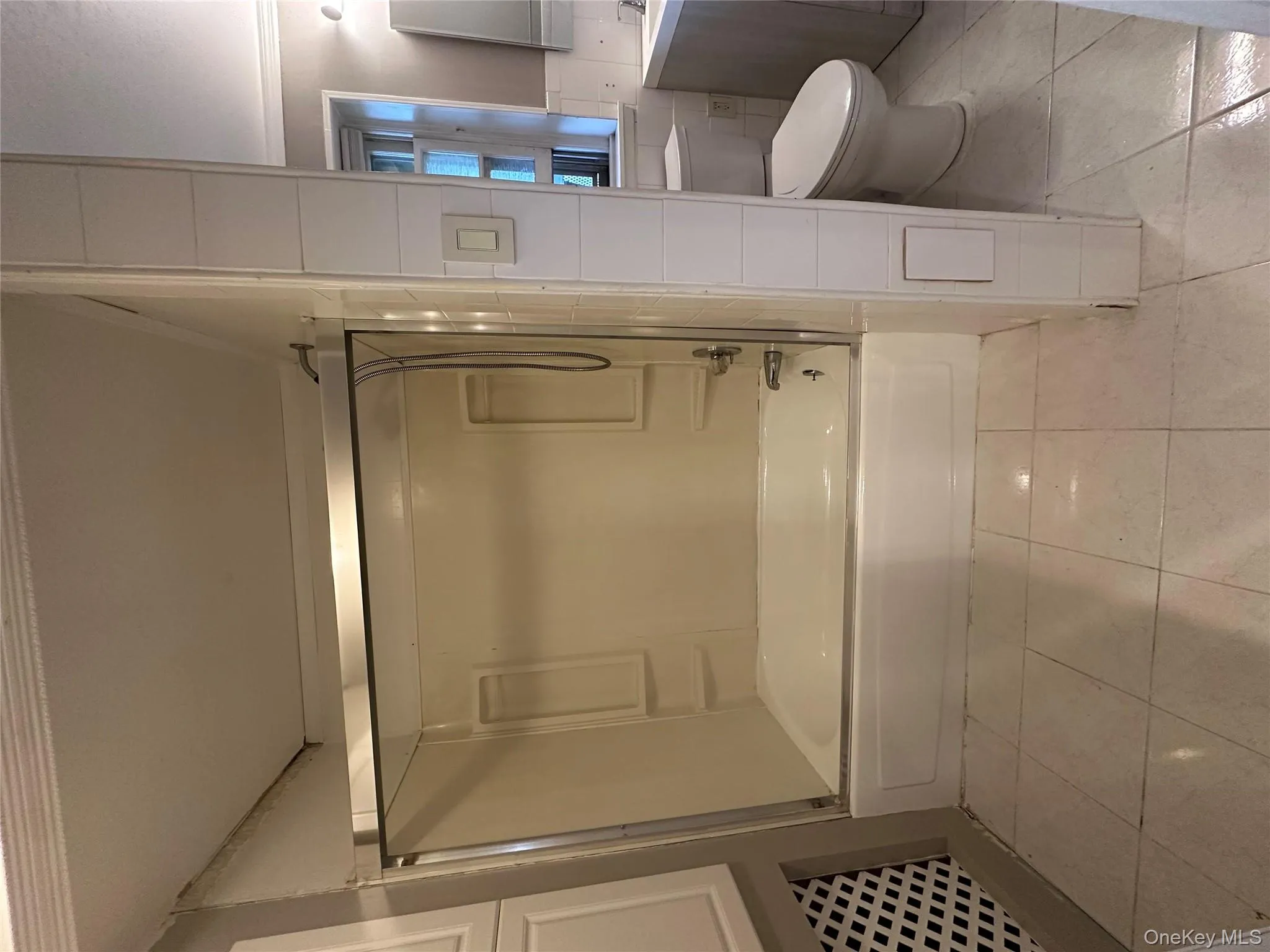Full bath featuring tub / shower combination, tile walls, vanity, and light tile patterned floors Full bath featuring tub / shower combination, tile walls, vanity, and light tile patterned floors