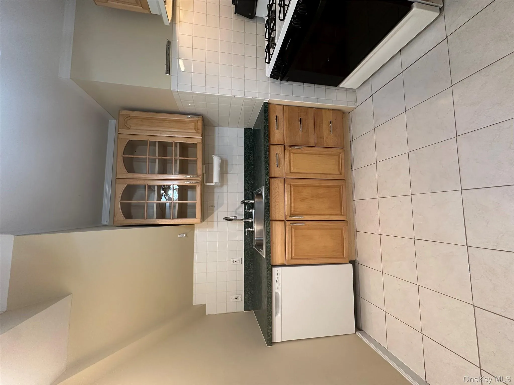 Kitchen with range, dark countertops, brown cabinets, dishwasher, and light tile patterned flooring Kitchen with range, dark countertops, brown cabinets, dishwasher, and light tile patterned flooring