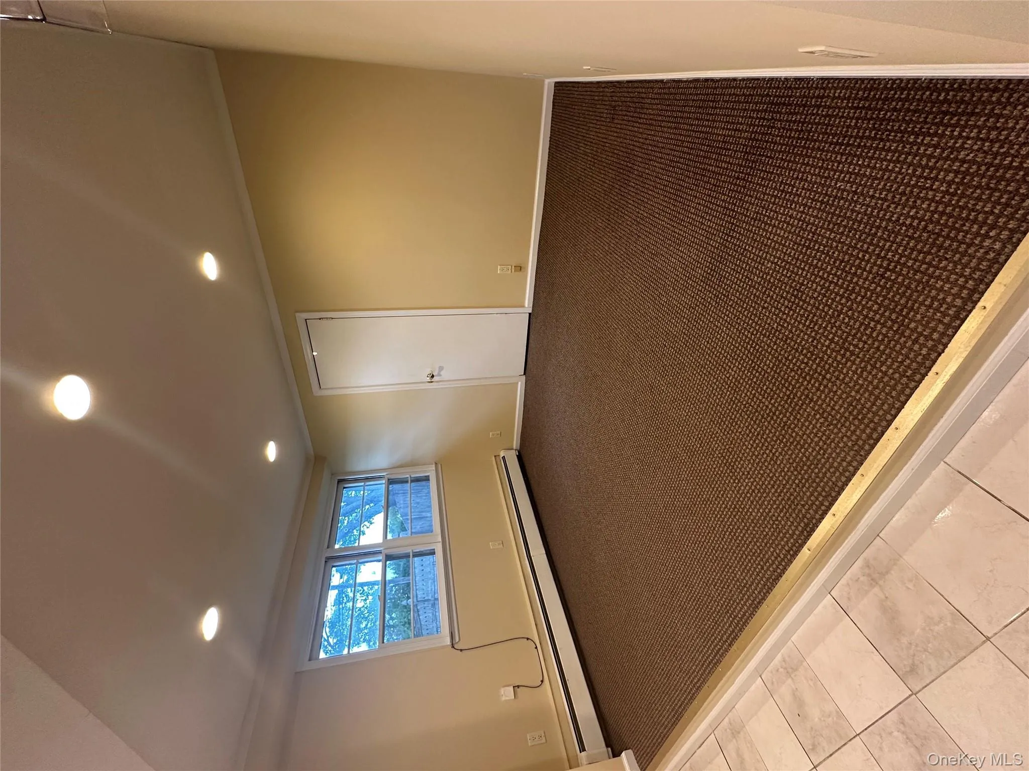 Spare room with recessed lighting, baseboard heating, crown molding, light colored carpet, and light tile patterned floors Spare room with recessed lighting, baseboard heating, crown molding, light colored carpet, and light tile patterned floors