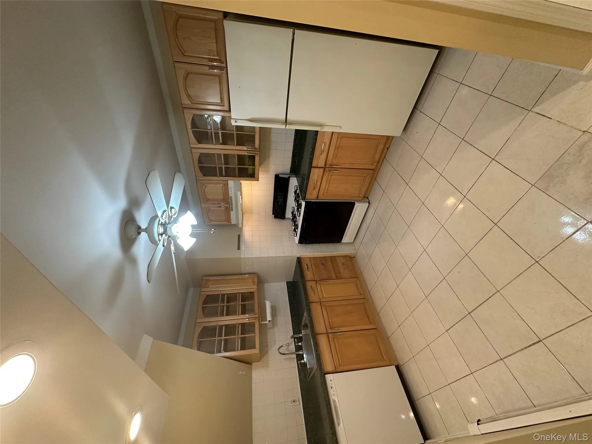 Kitchen with glass insert cabinets, refrigerator, black range with gas cooktop, and tasteful backsplash Kitchen with glass insert cabinets, refrigerator, black range with gas cooktop, and tasteful backsplash